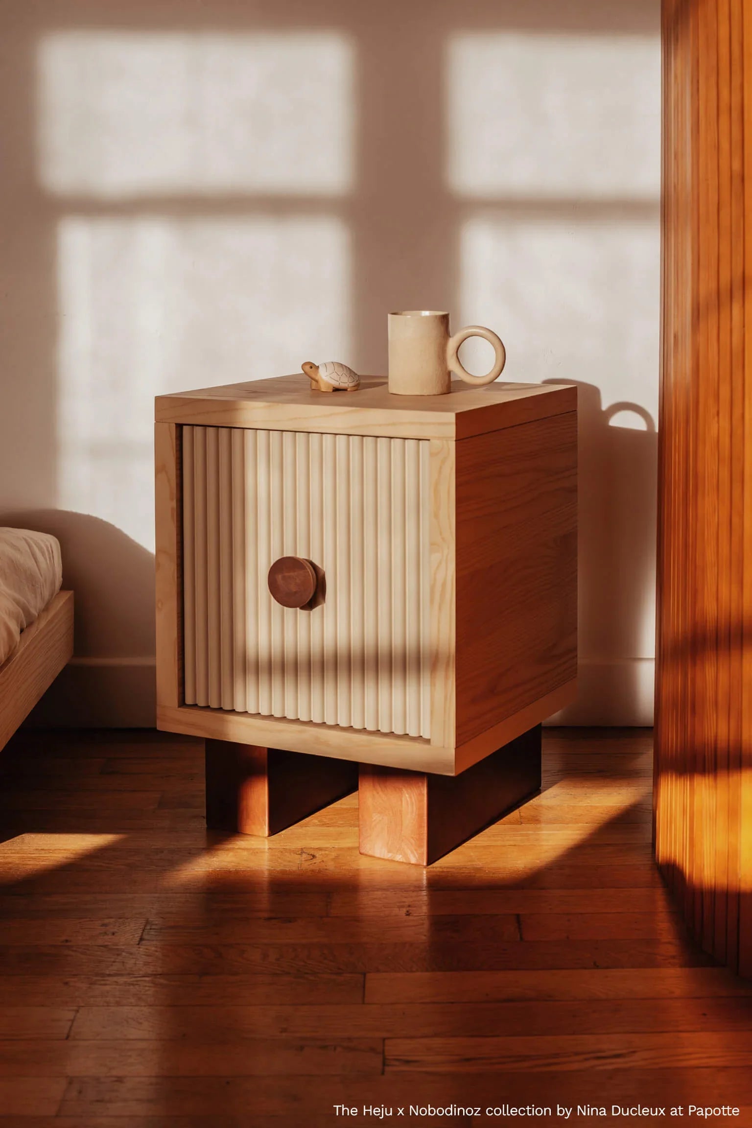 Heju x Nobodinoz wooden bedside table with fluted beige door in sunlit bedroom