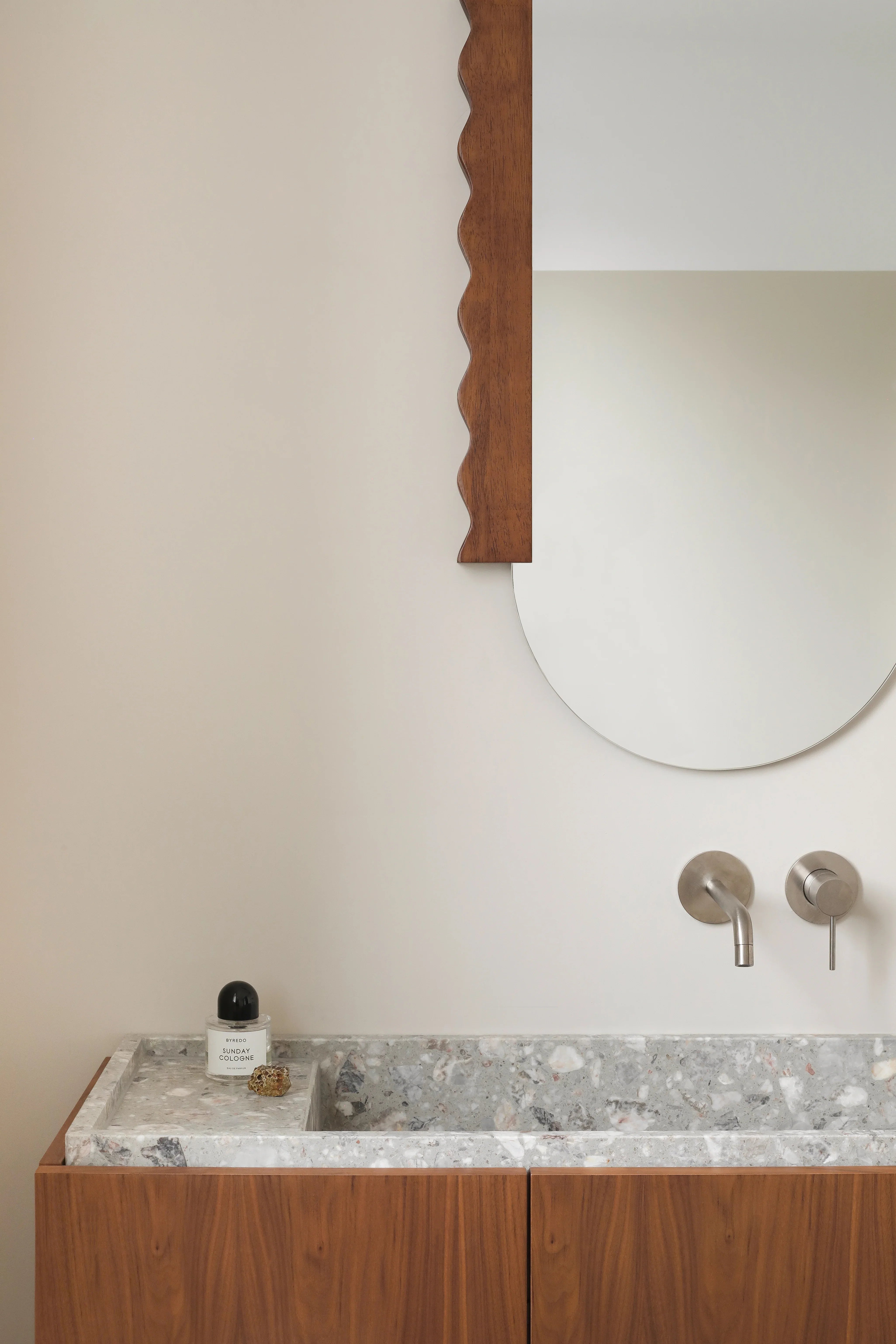 Heju x Nobodinoz wood-framed mirror above a terrazzo sink and walnut vanity in a modern bathroom