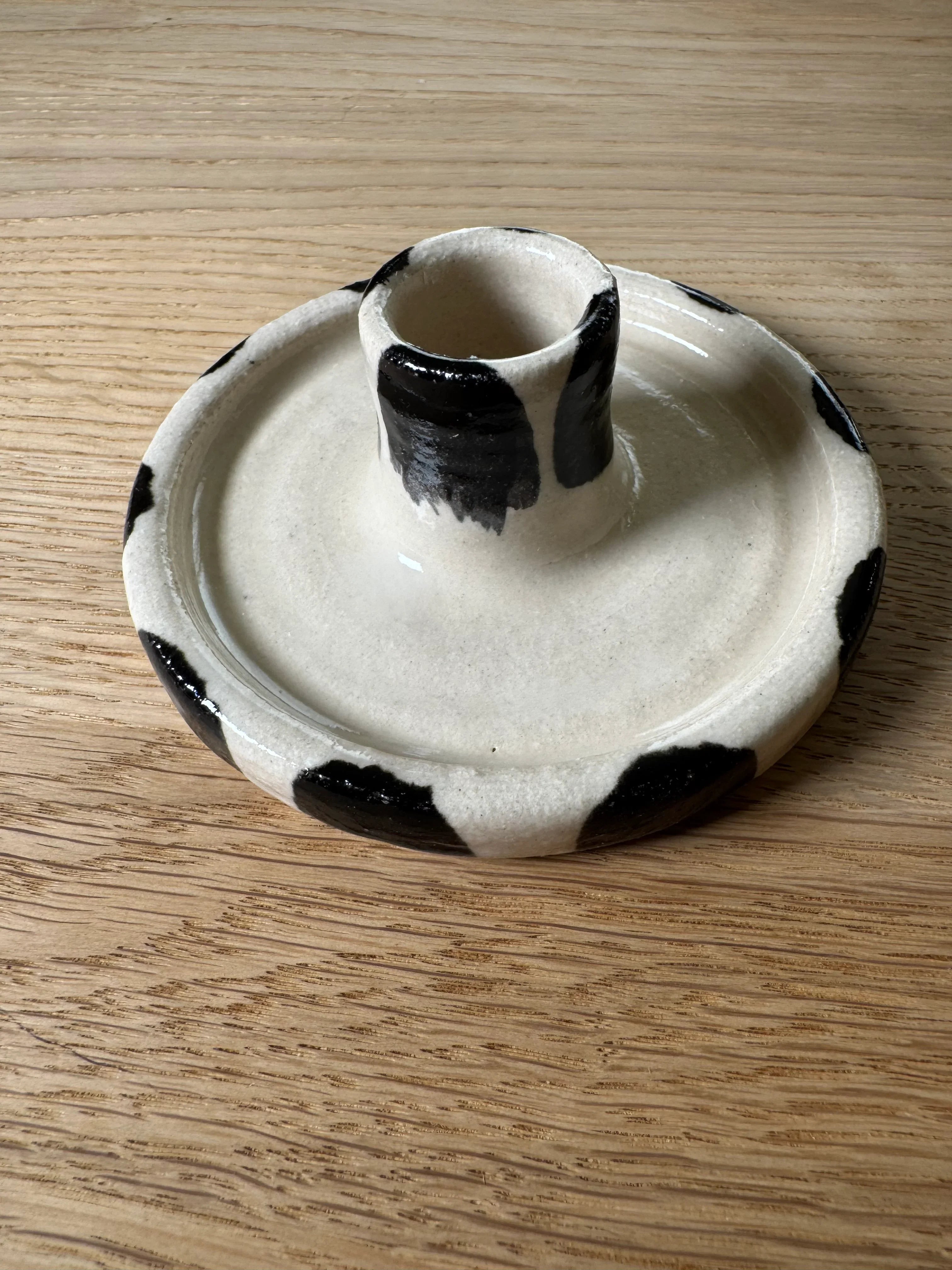 Wooj ceramic candle holder in cream with black cow print details on wooden surface