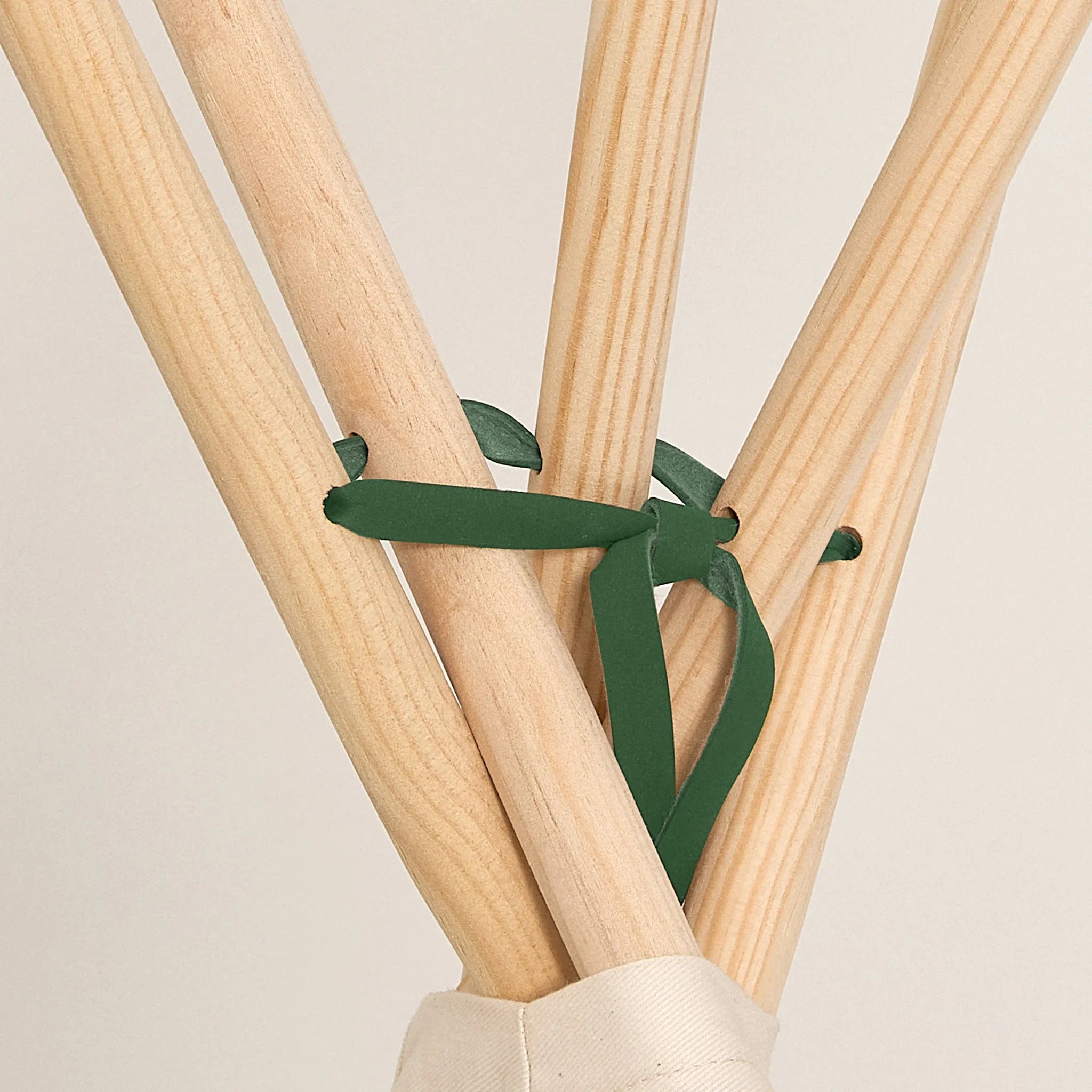 Nobodinoz Arizona teepee natural wood poles with green cotton tie, close-up.