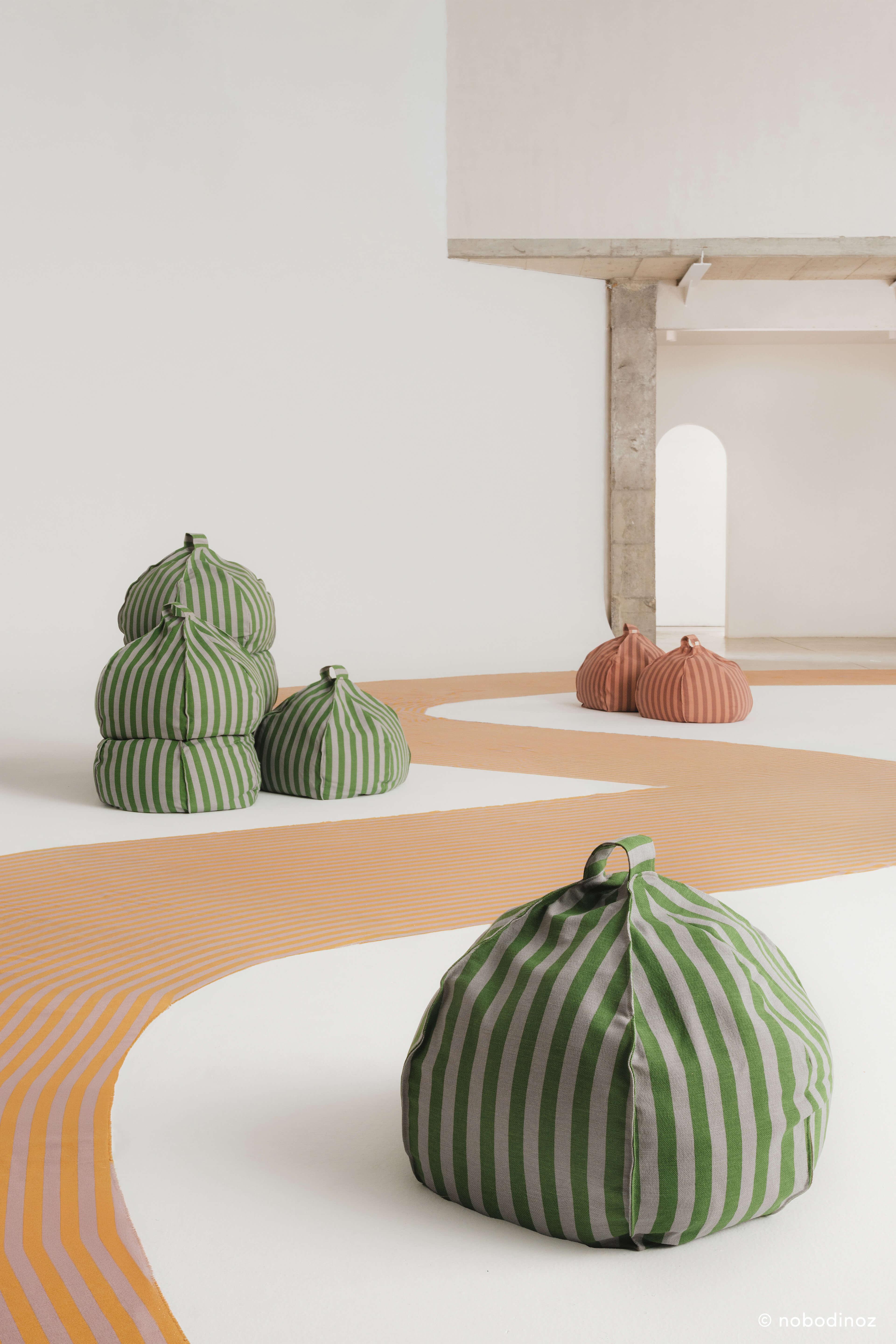 Nobodinoz round cotton bean bags in green and pink mauve stripes in a modern room