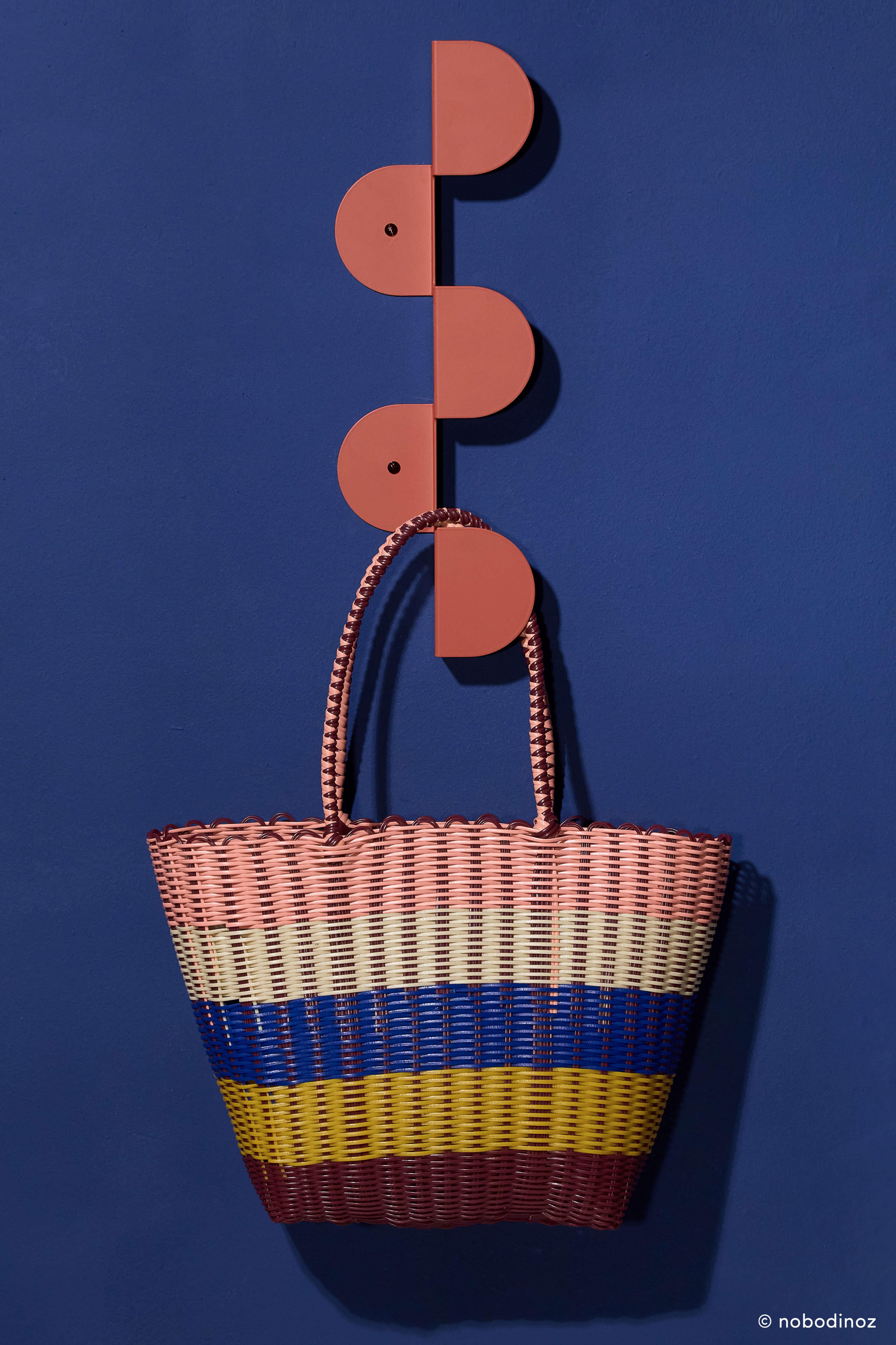 Nobodinoz burnt red steel wall coat rack with colorful woven basket on blue wall