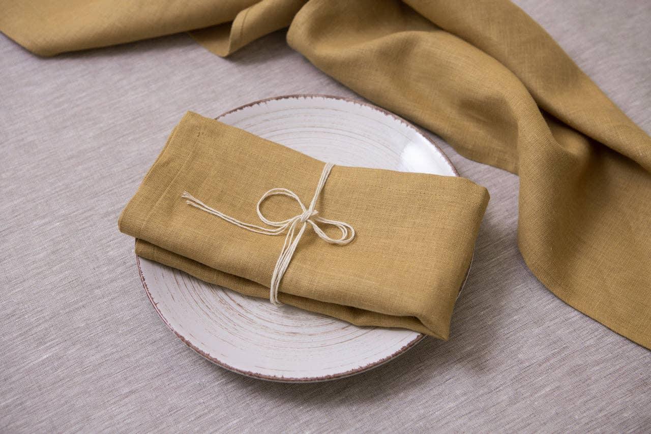 Linen Tales mustard linen napkin on plate, tied with string, premium table setting