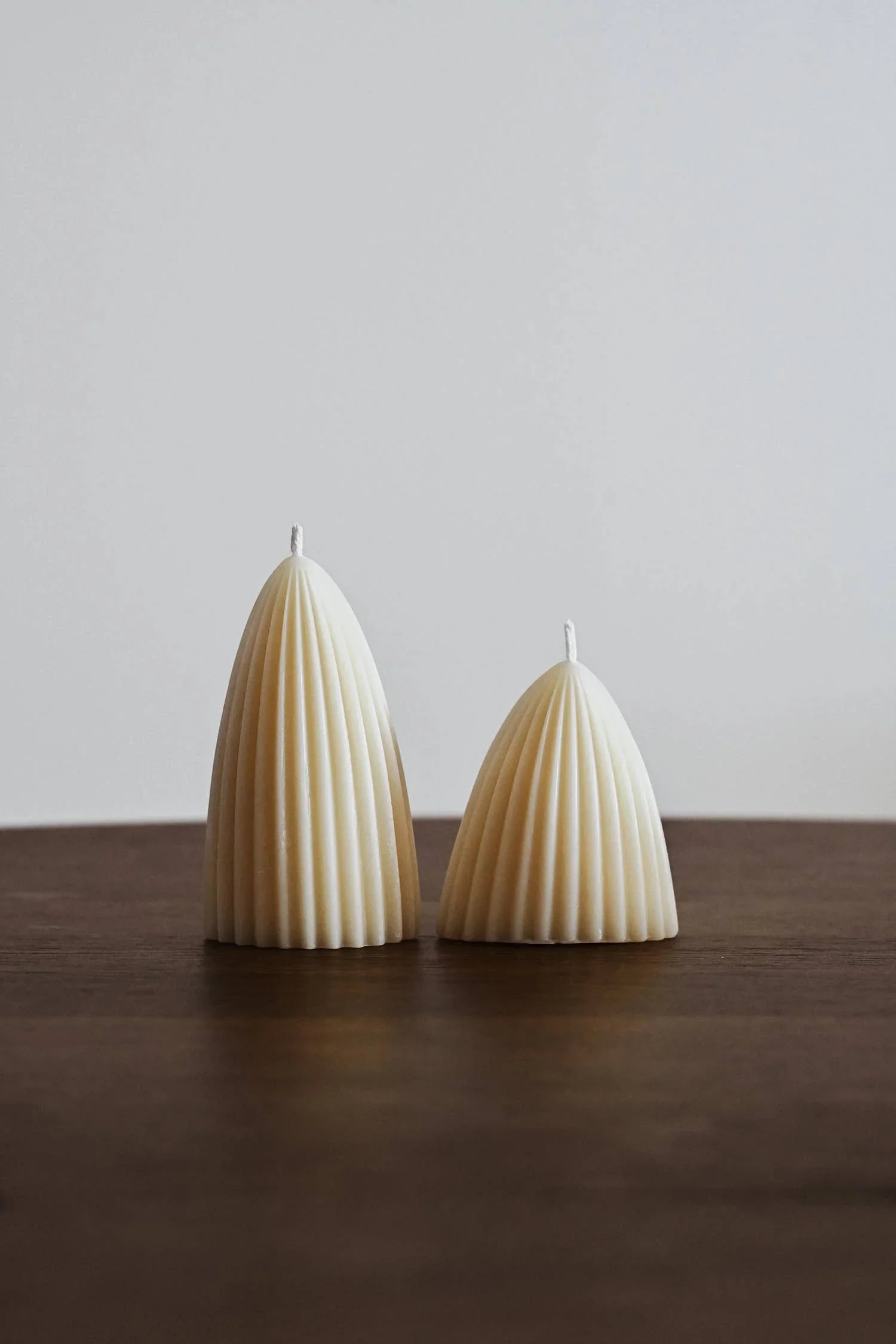 Aoiro beige beeswax ribbed candles set on a dark wood surface