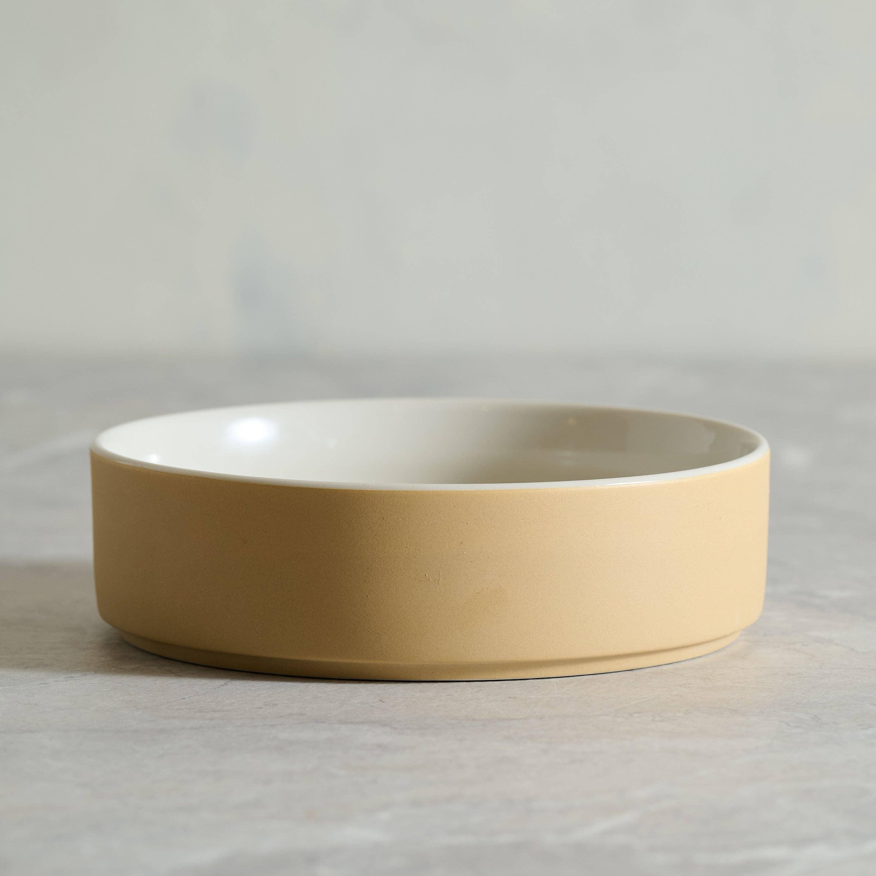 Fable ceramic dog bowl in matte beige and glossy white finish on a neutral surface