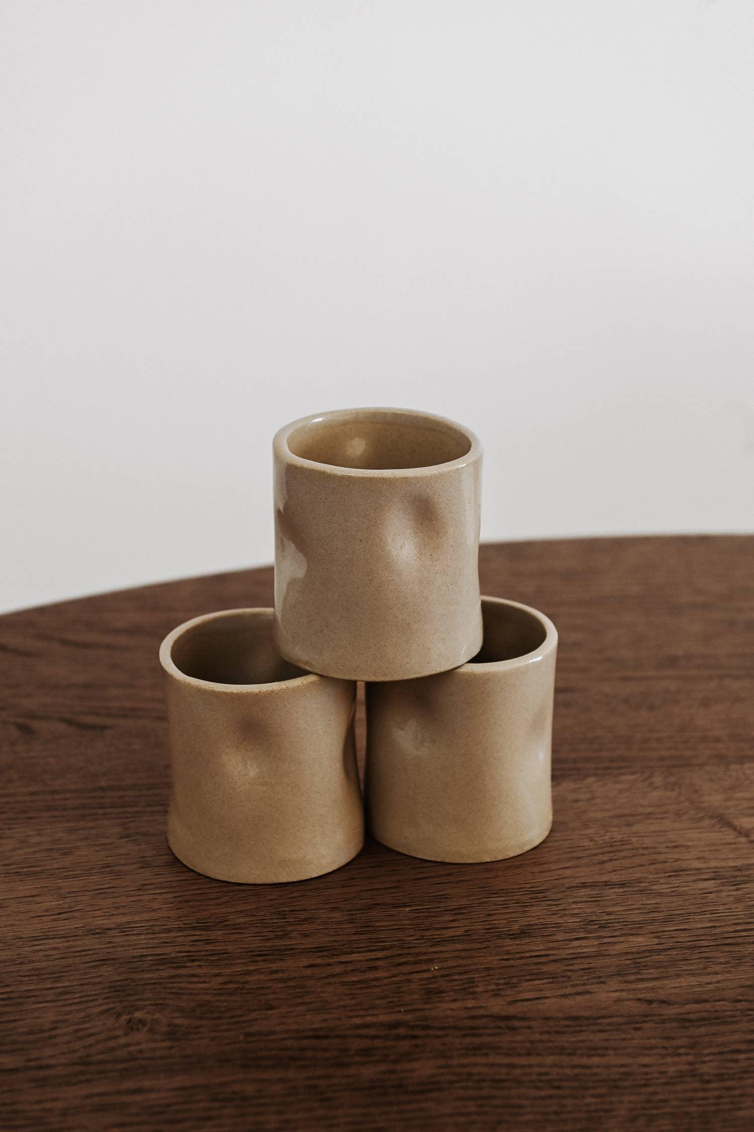 Mira Blackman beige ceramic cups with organic texture on wood table