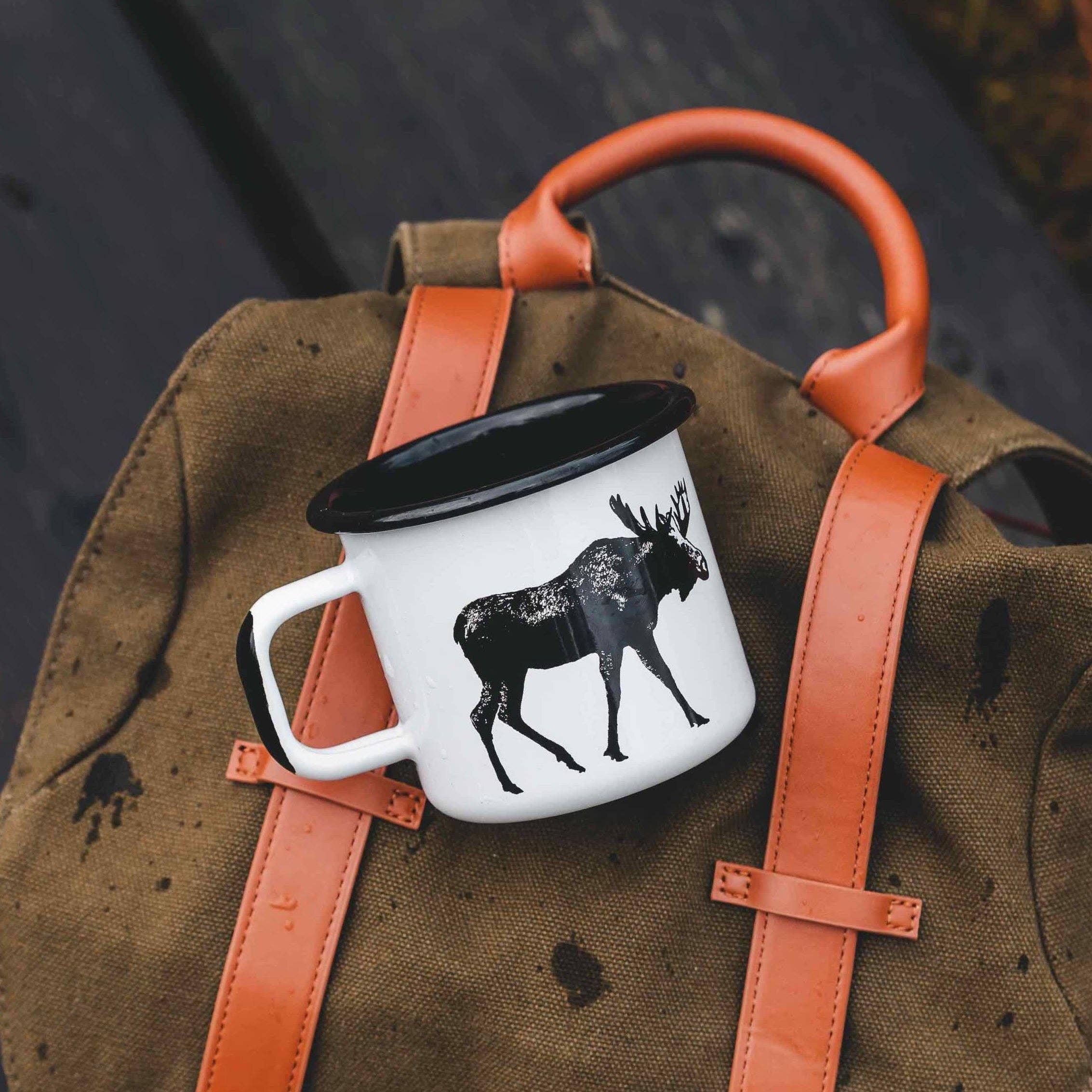 Crow Canyon Home enamel mug with black moose print on canvas and leather backpack