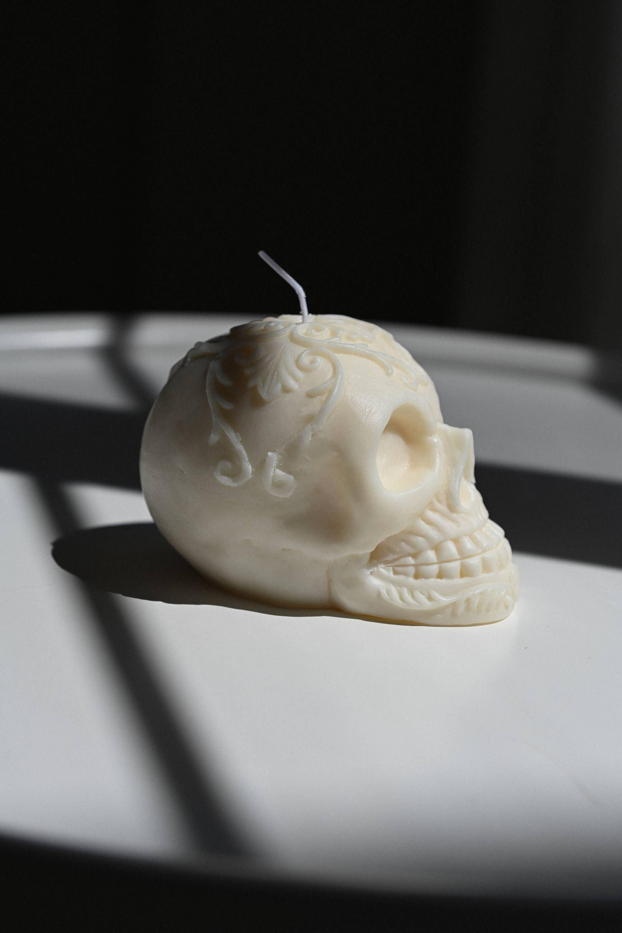 Nata Concept Store ivory skull-shaped soy wax candle with ornate carved details on a white table