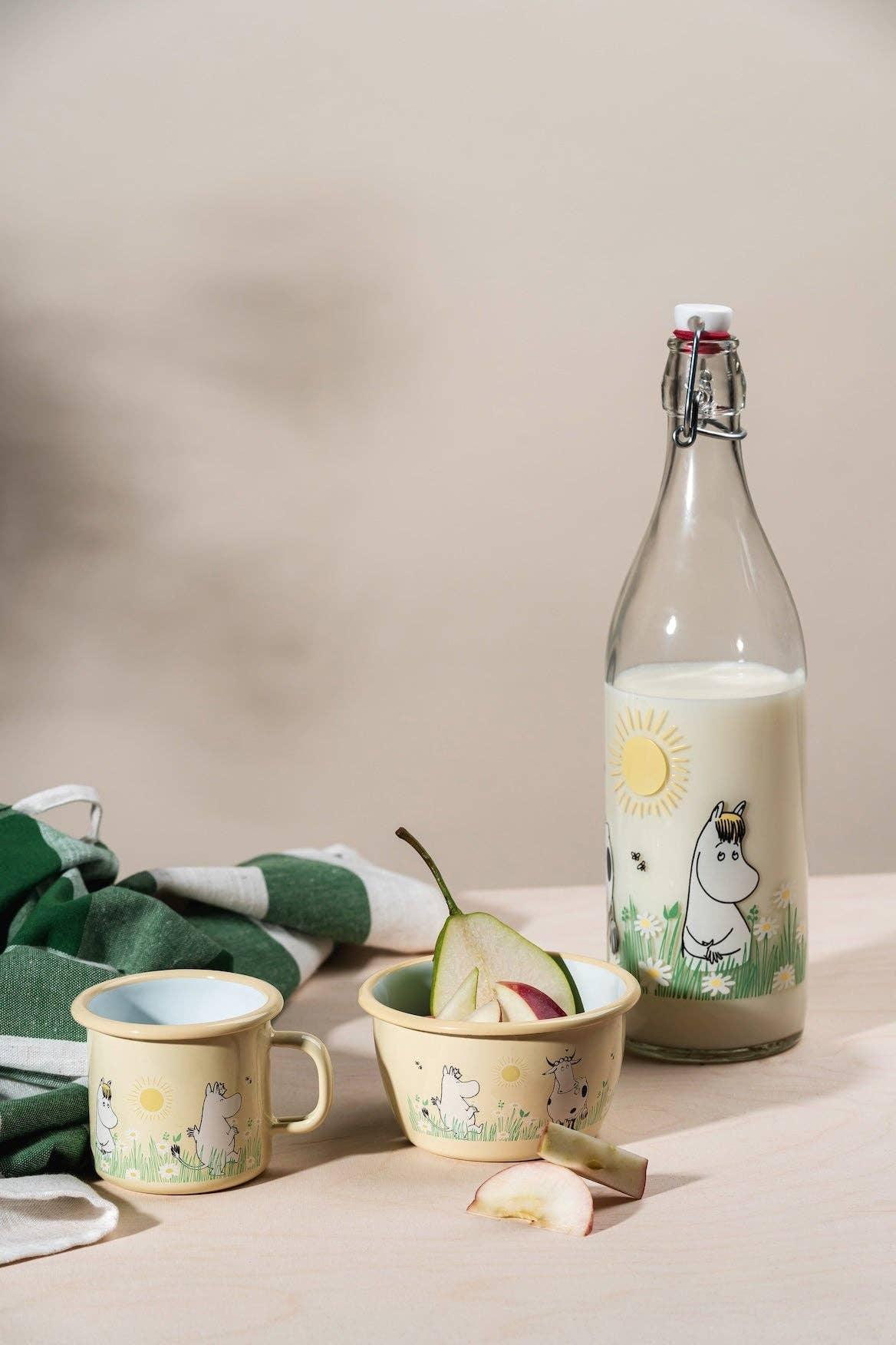 Moomin enamel cup, bowl, and glass milk bottle with yellow and green illustrations on beige background
