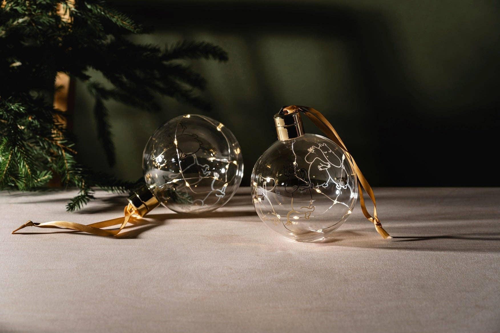 Muurla glass Christmas baubles with gold caps and ribbon, clear with white line art, on table
