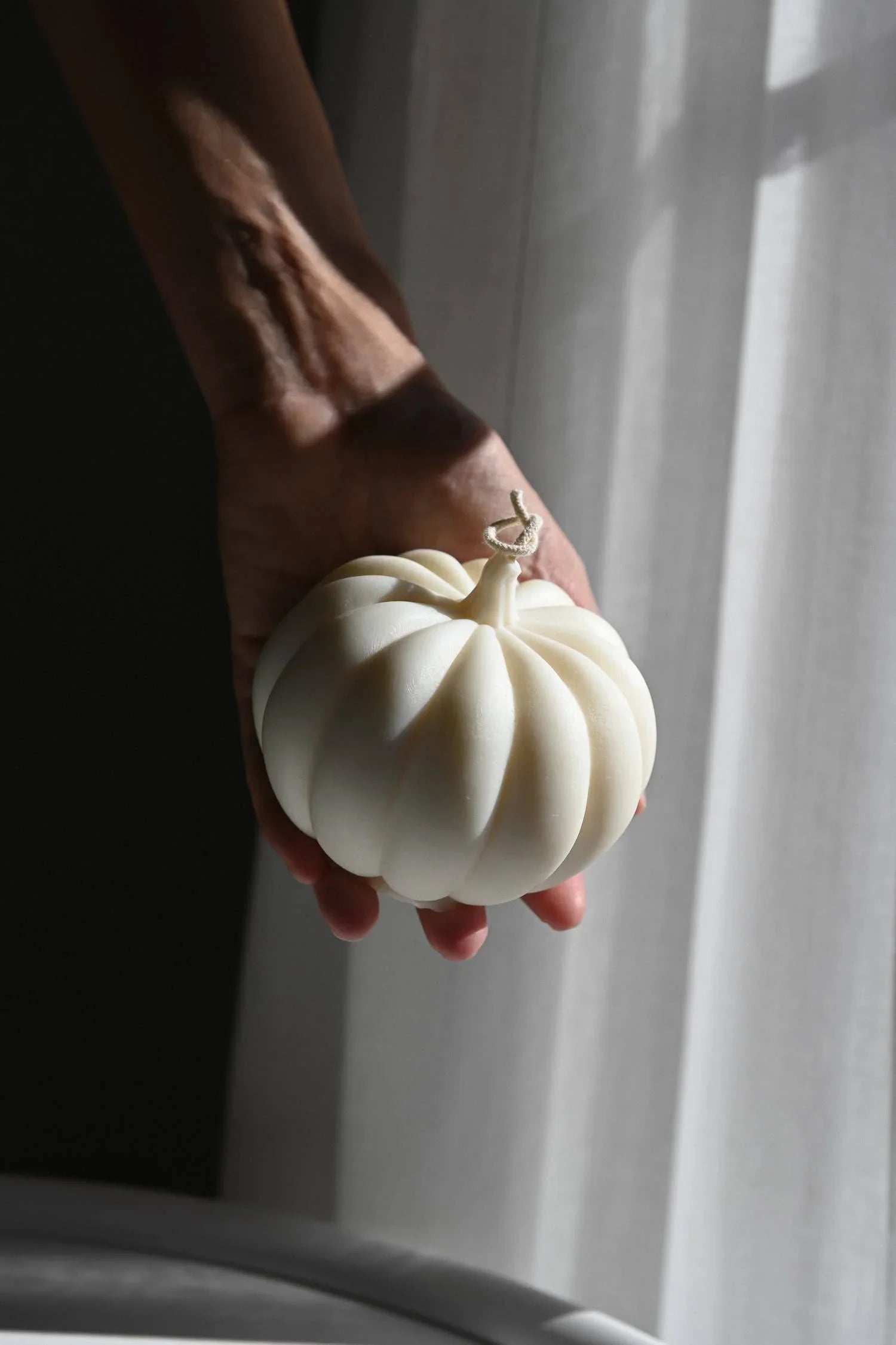 Cocod'or white pumpkin-shaped soy wax candle held in hand, minimalist style