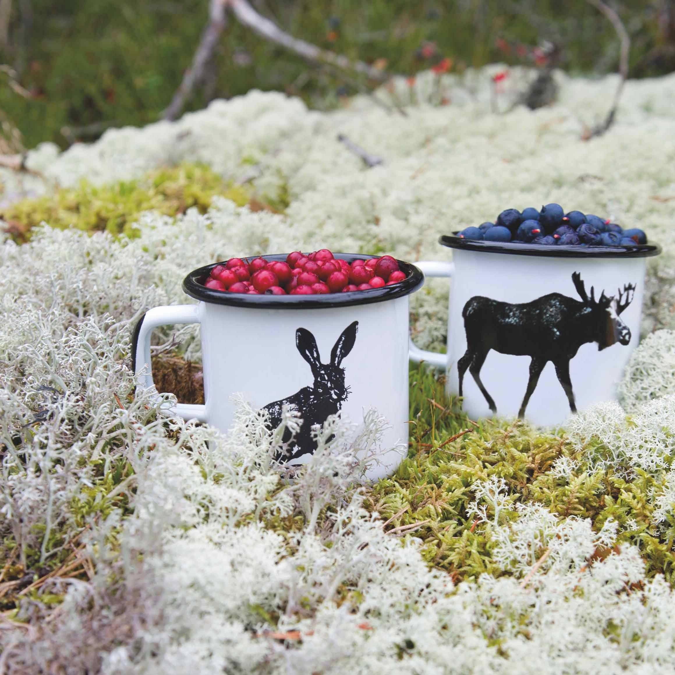 Muurla enamel mugs with black animal prints, white color, filled with berries on moss.