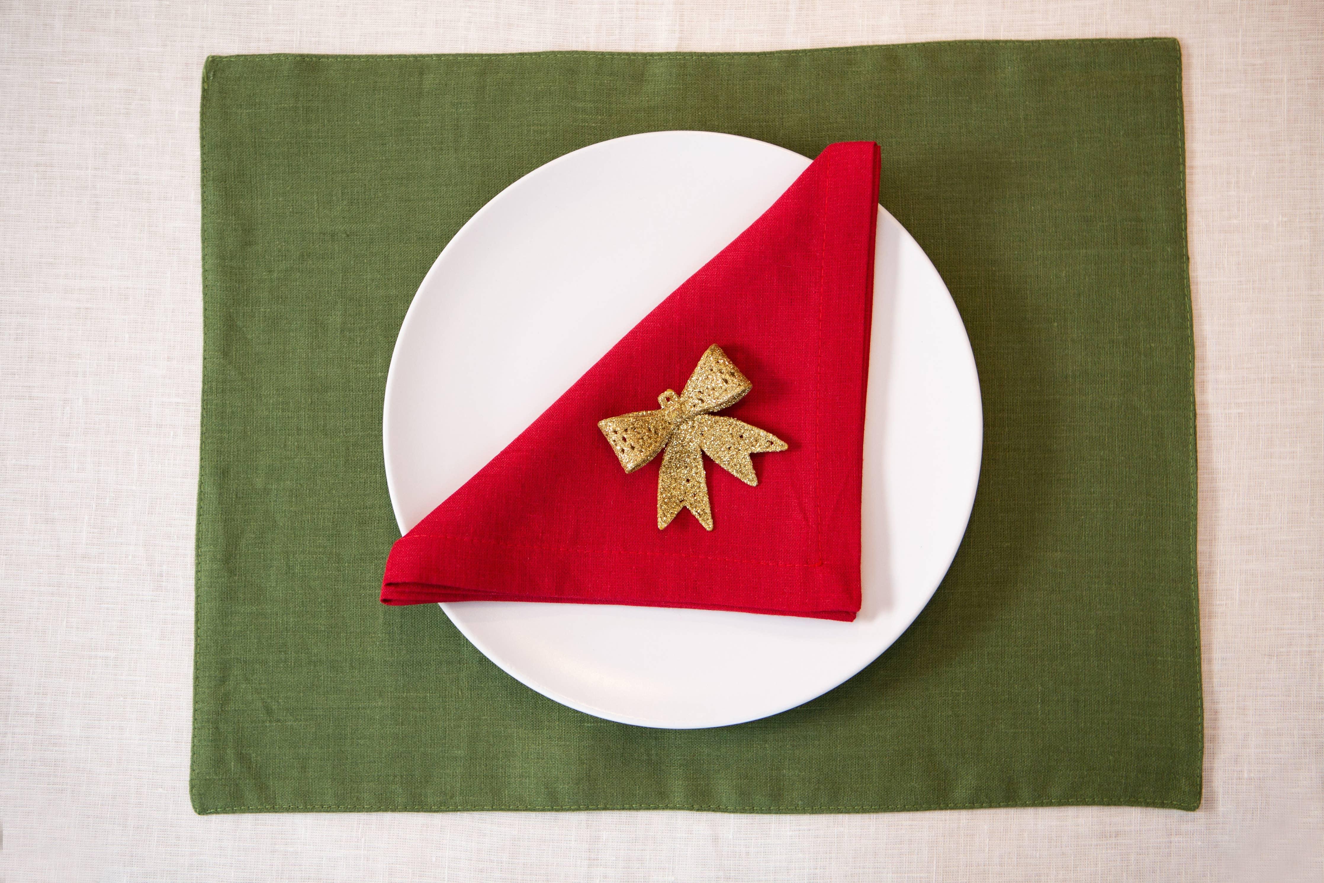 Maison Septembre green linen placemat, white plate, red linen napkin, gold bow accent