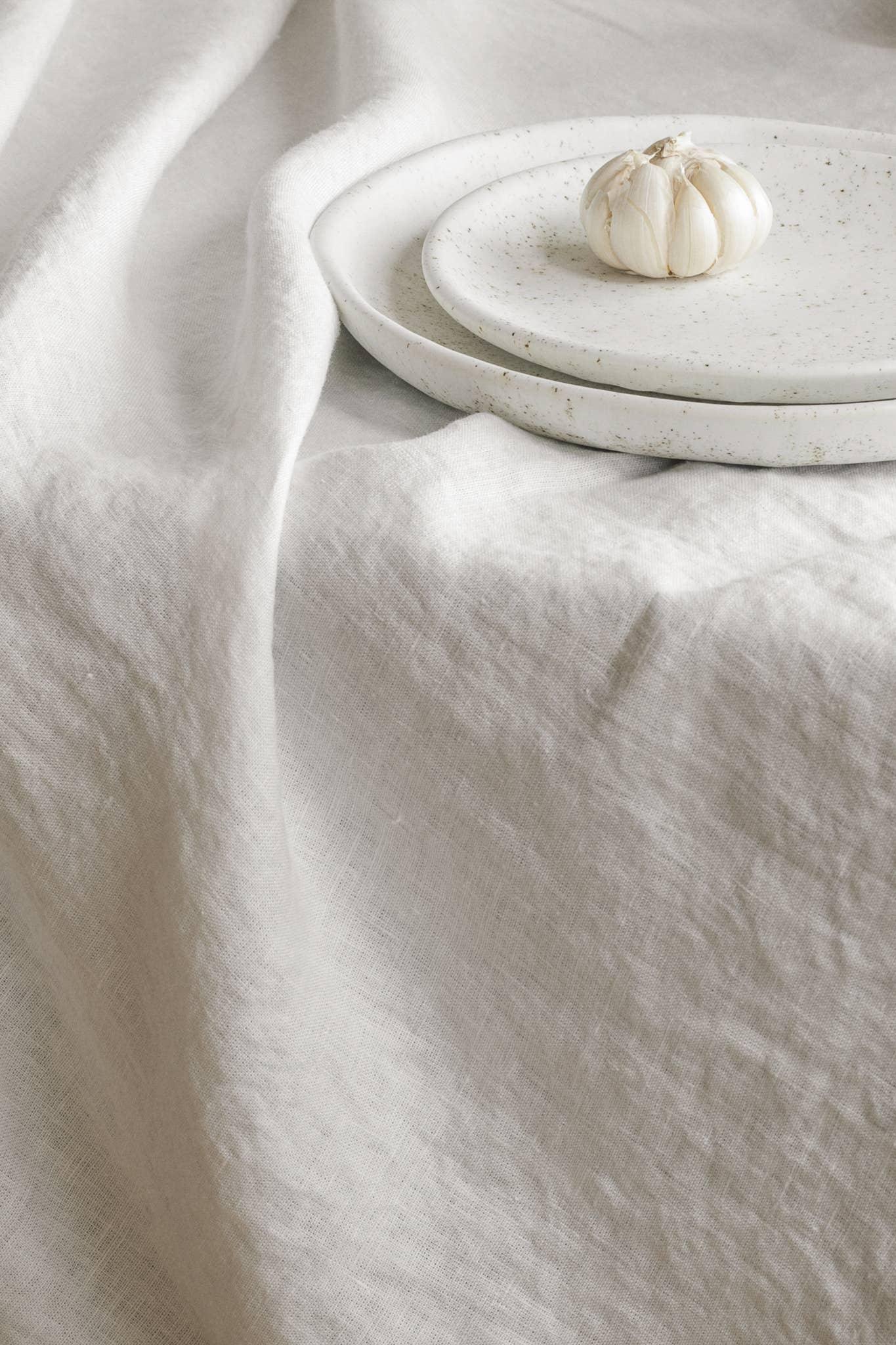 Fog Linen Work linen tablecloth with white speckled ceramic plates and garlic bulb