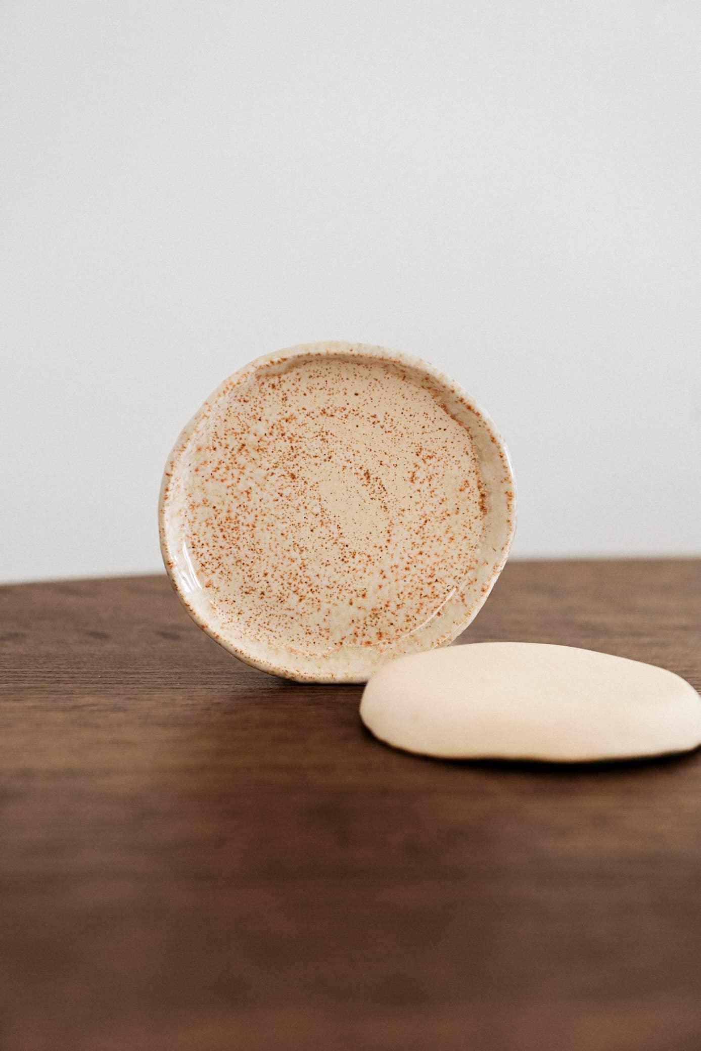 Speckled ceramic dish by Fable in beige, minimalist design on wooden surface