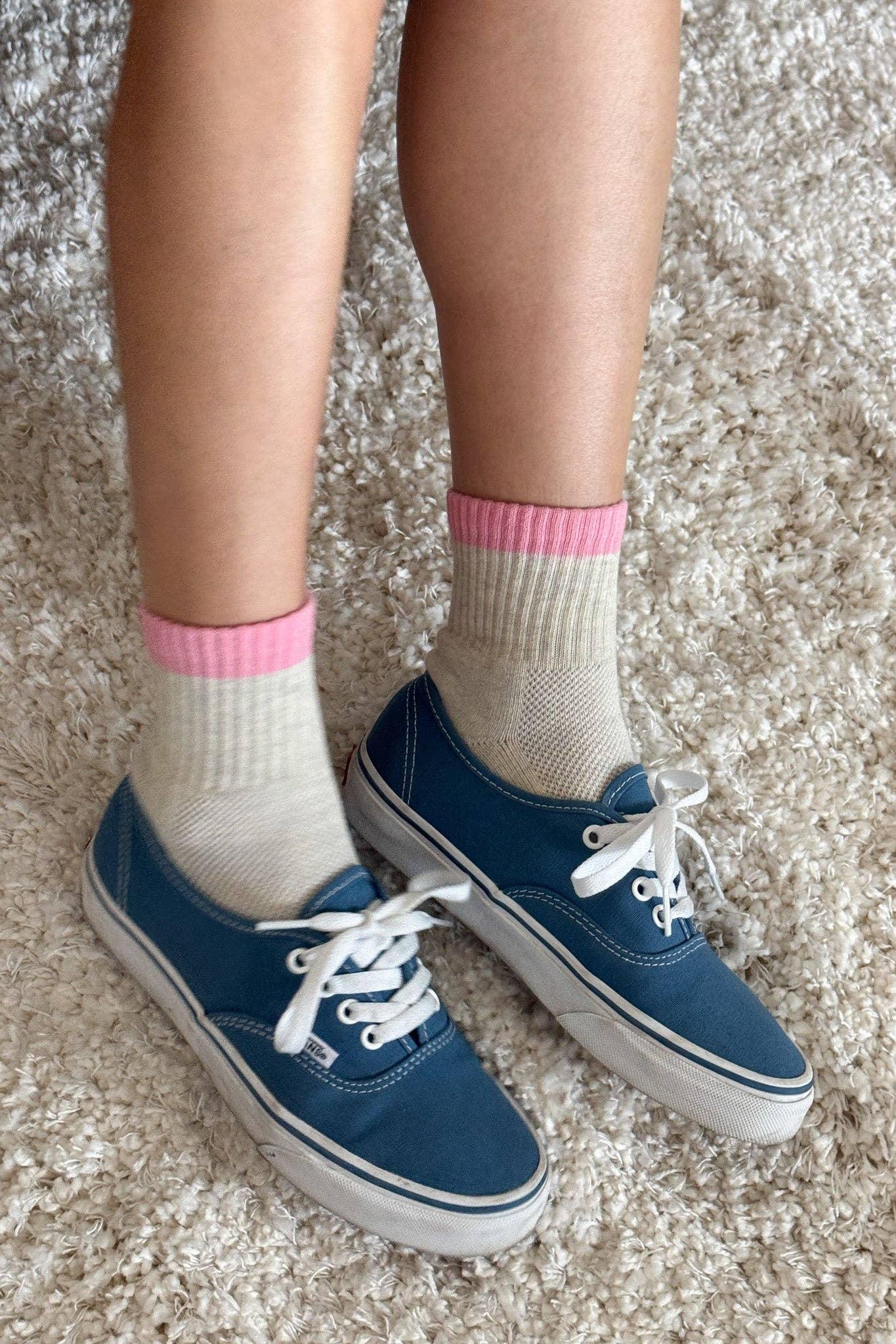 Vans blue canvas sneakers with white laces, cream socks with pink cuffs on textured carpet