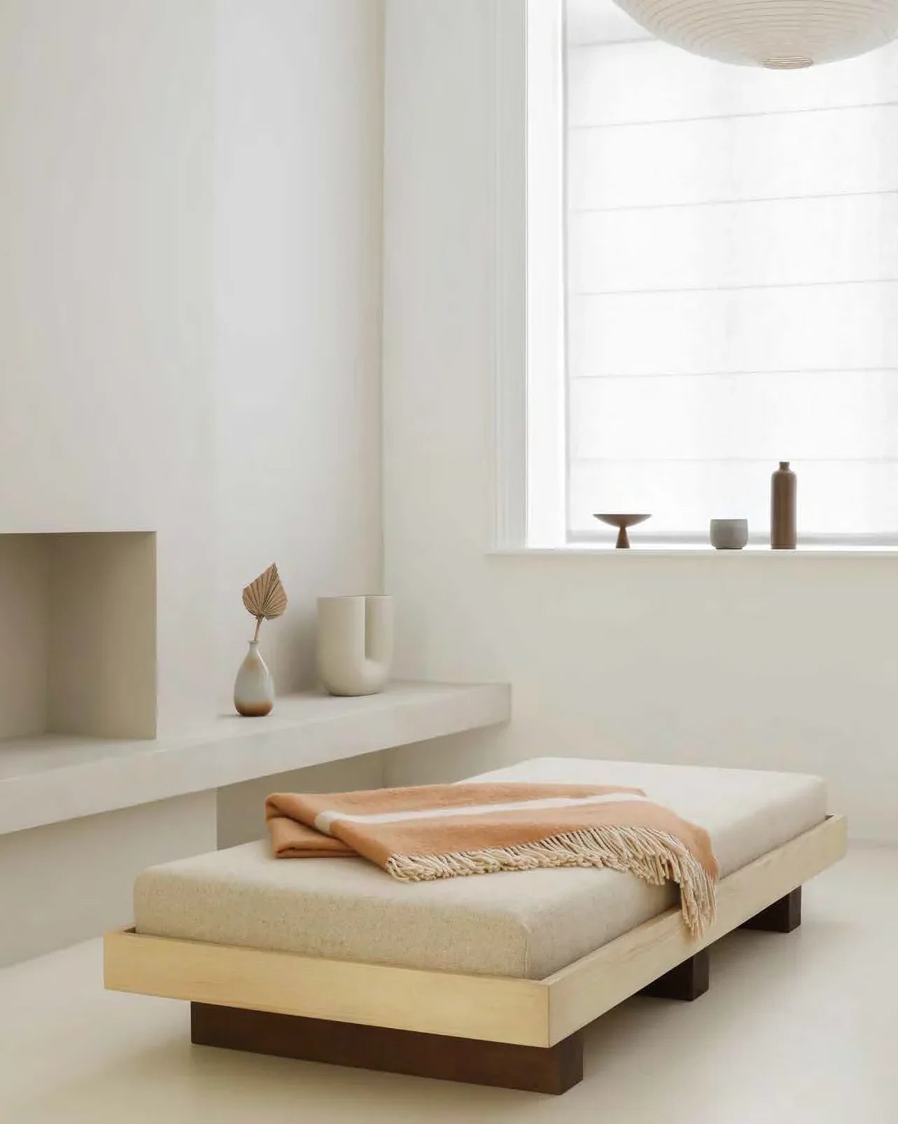 Coil Daybed in natural wood with beige fabric and tan throw, minimal modern interior
