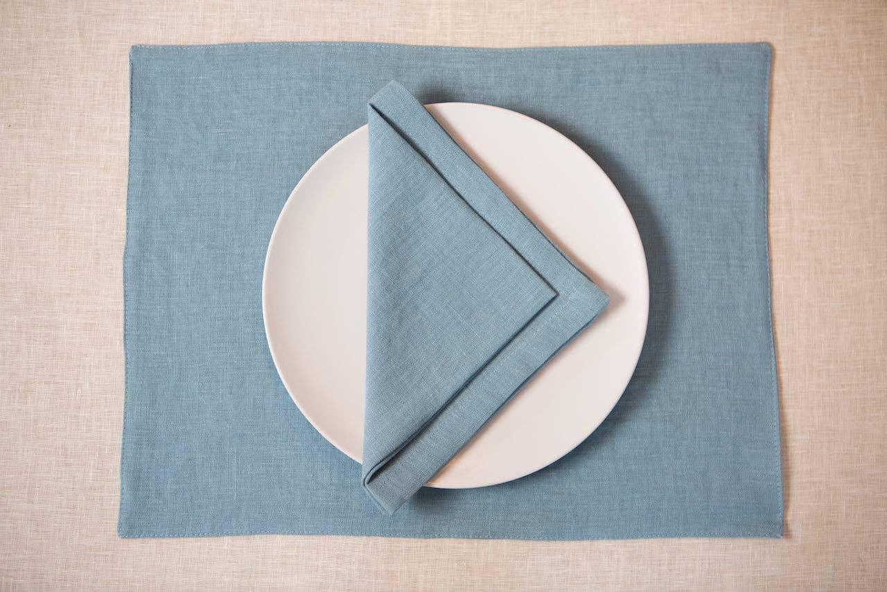 MagicLinen blue linen placemat and napkin set with white ceramic plate on neutral tablecloth