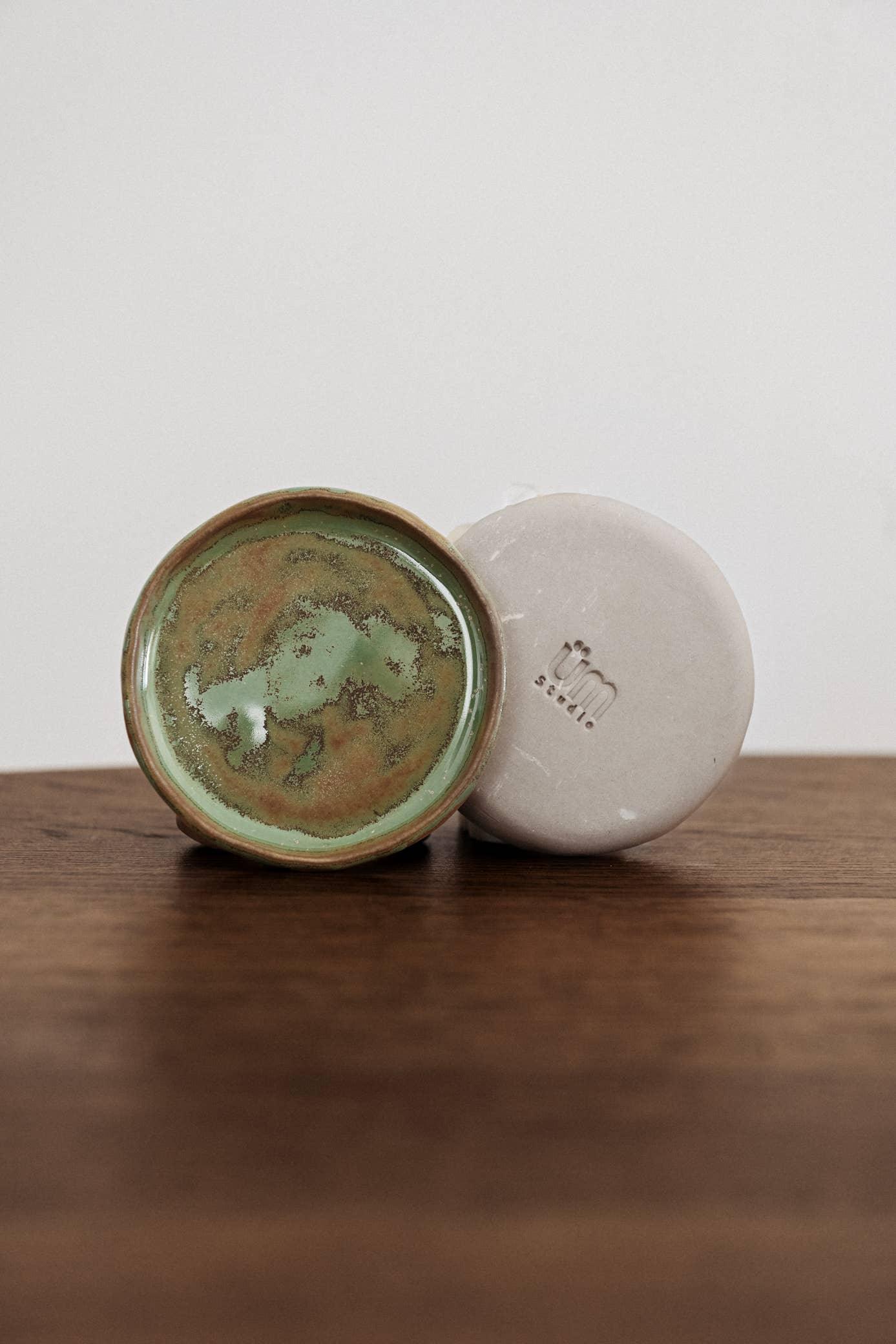 Umi Studio ceramic dish with green glaze and ivory soap bar, on wooden surface