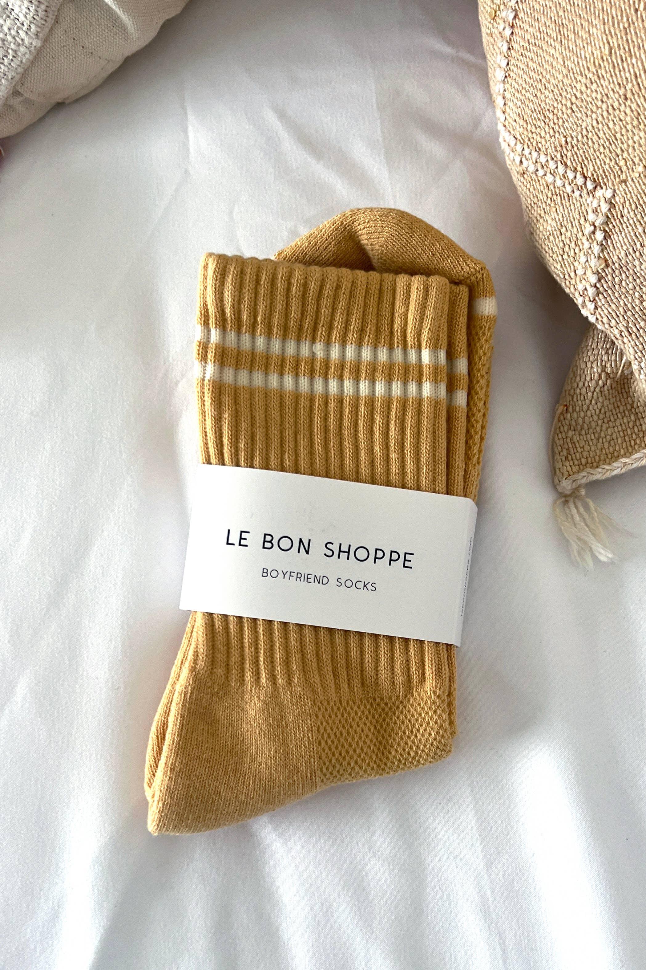 Le Bon Shoppe Boyfriend Socks in mustard yellow cotton with white stripes, folded on white bedding