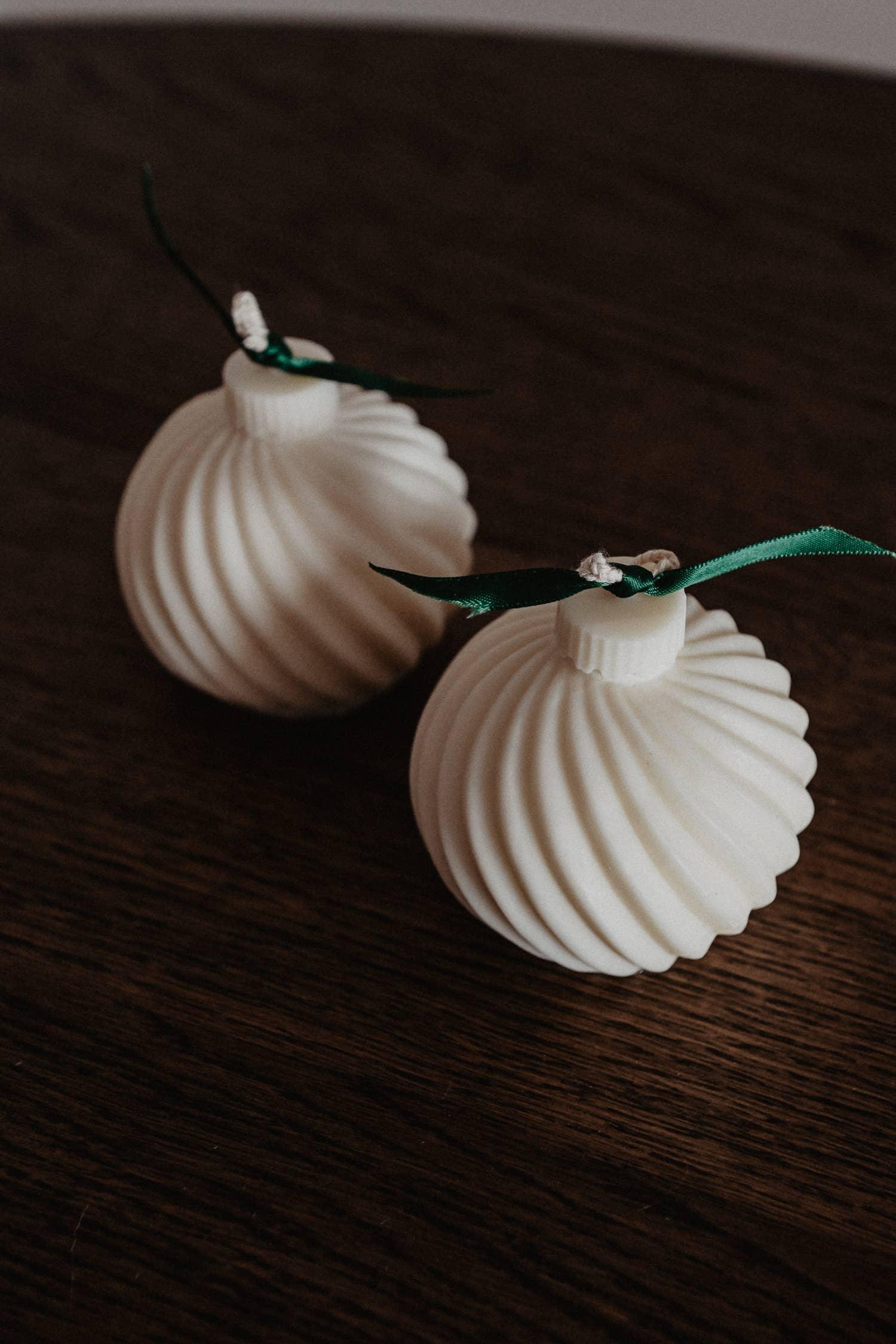 Friday Collective white soy wax sculpted candles with green ribbon on dark wood table