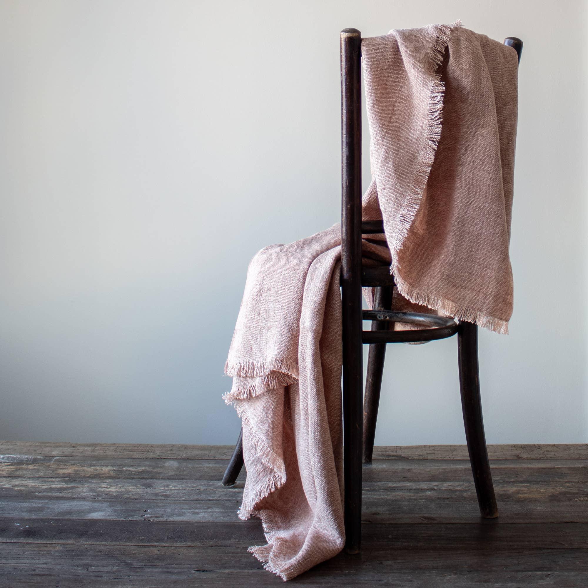 Maison de Vacances linen throw in blush pink draped on dark wood chair