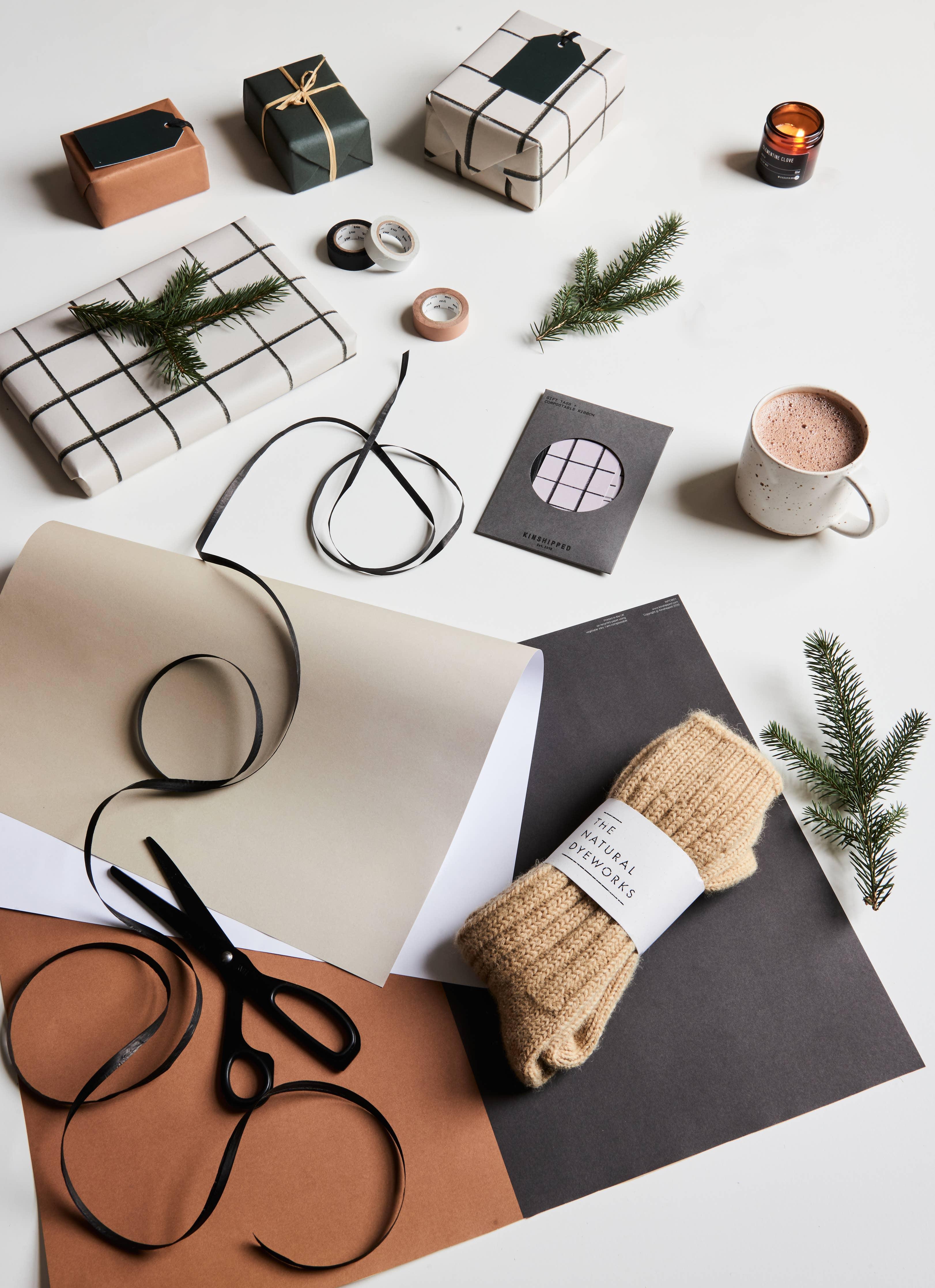 The Natural Dyeworks beige wool socks, gift wrapping supplies, and holiday decor flat lay
