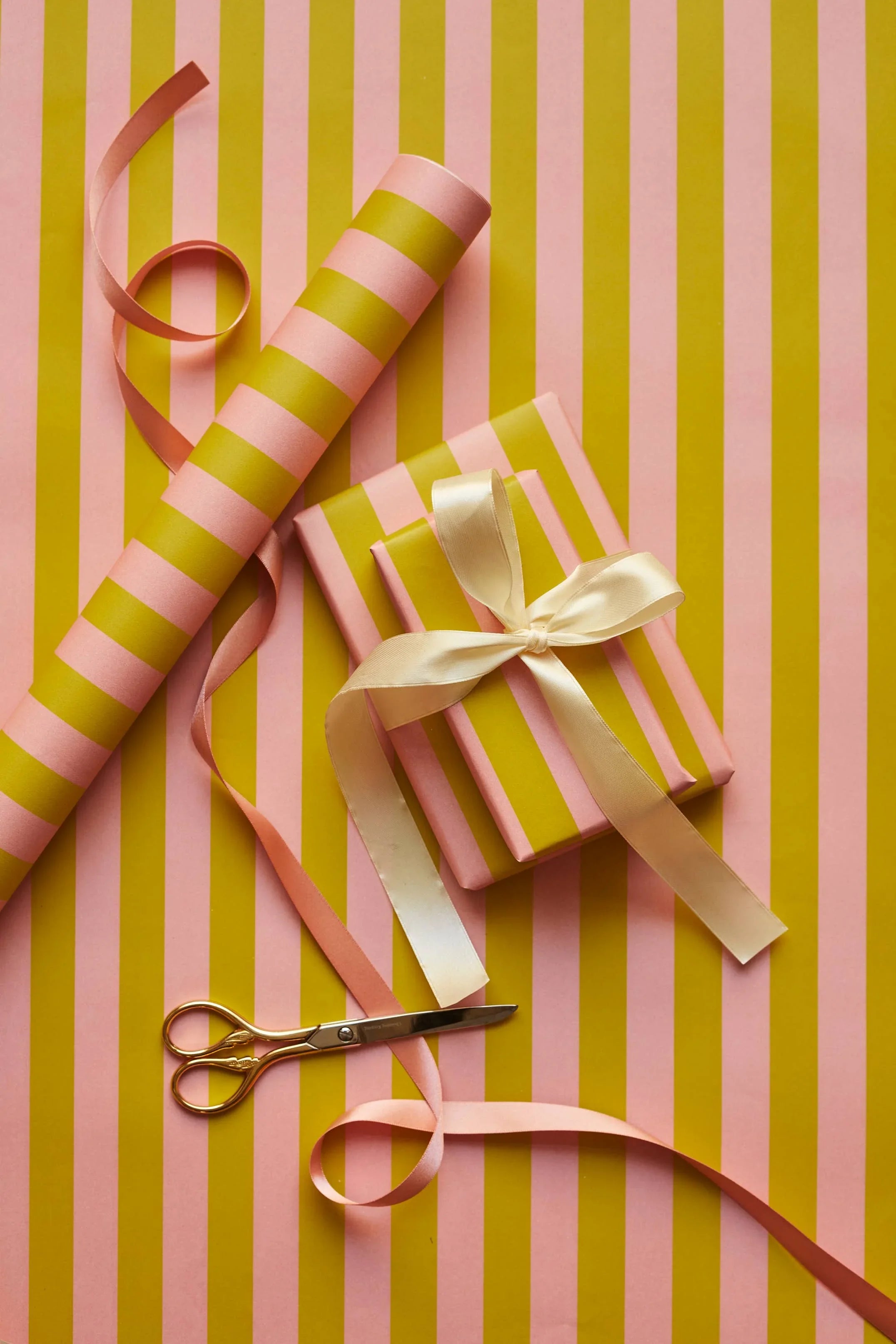 Rifle Paper Co. pink and gold striped gift wrap, gold scissors, and gift box with satin ribbon