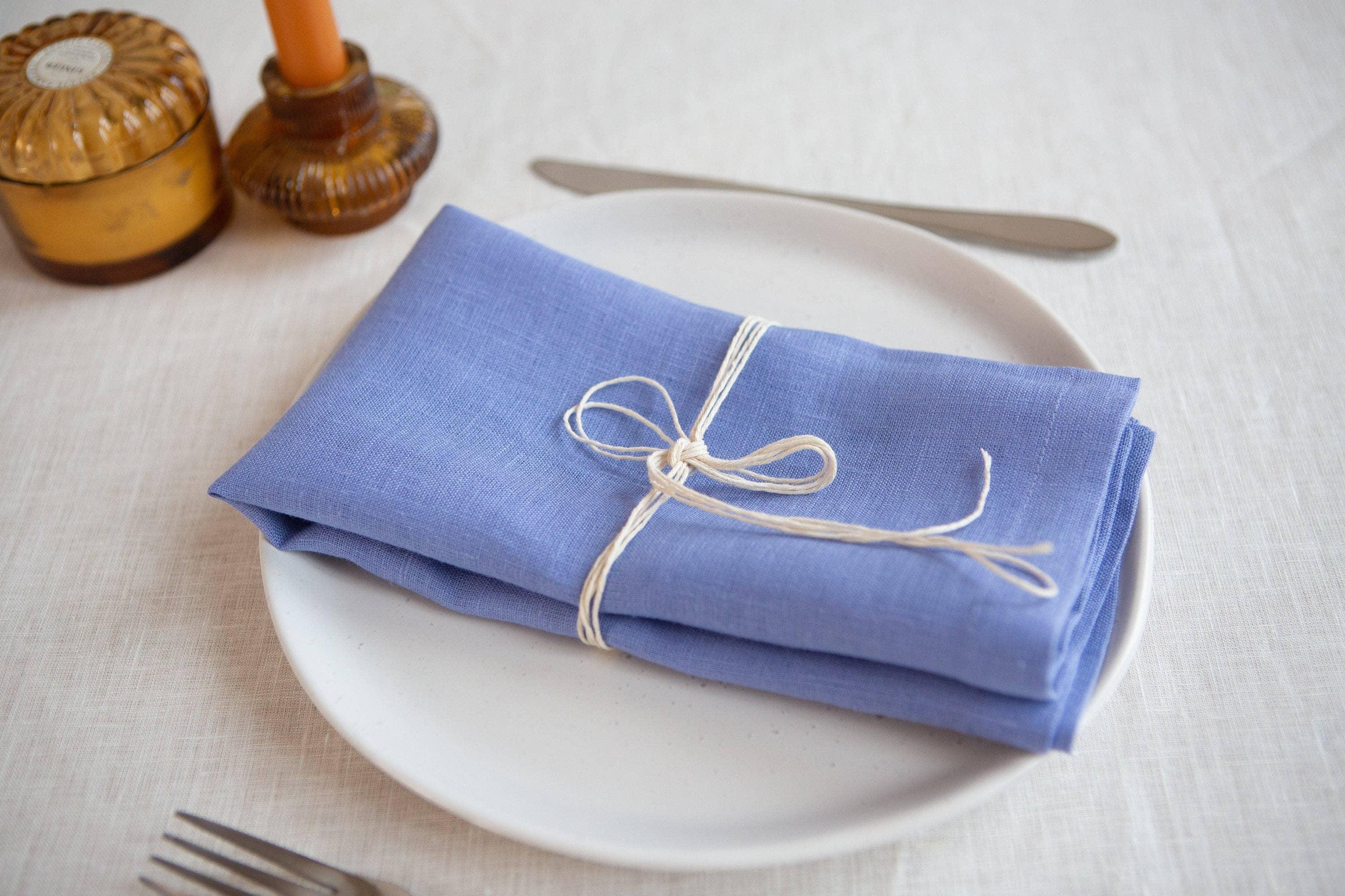 MagicLinen blue linen napkin tied with string on a white plate, elegant table setting