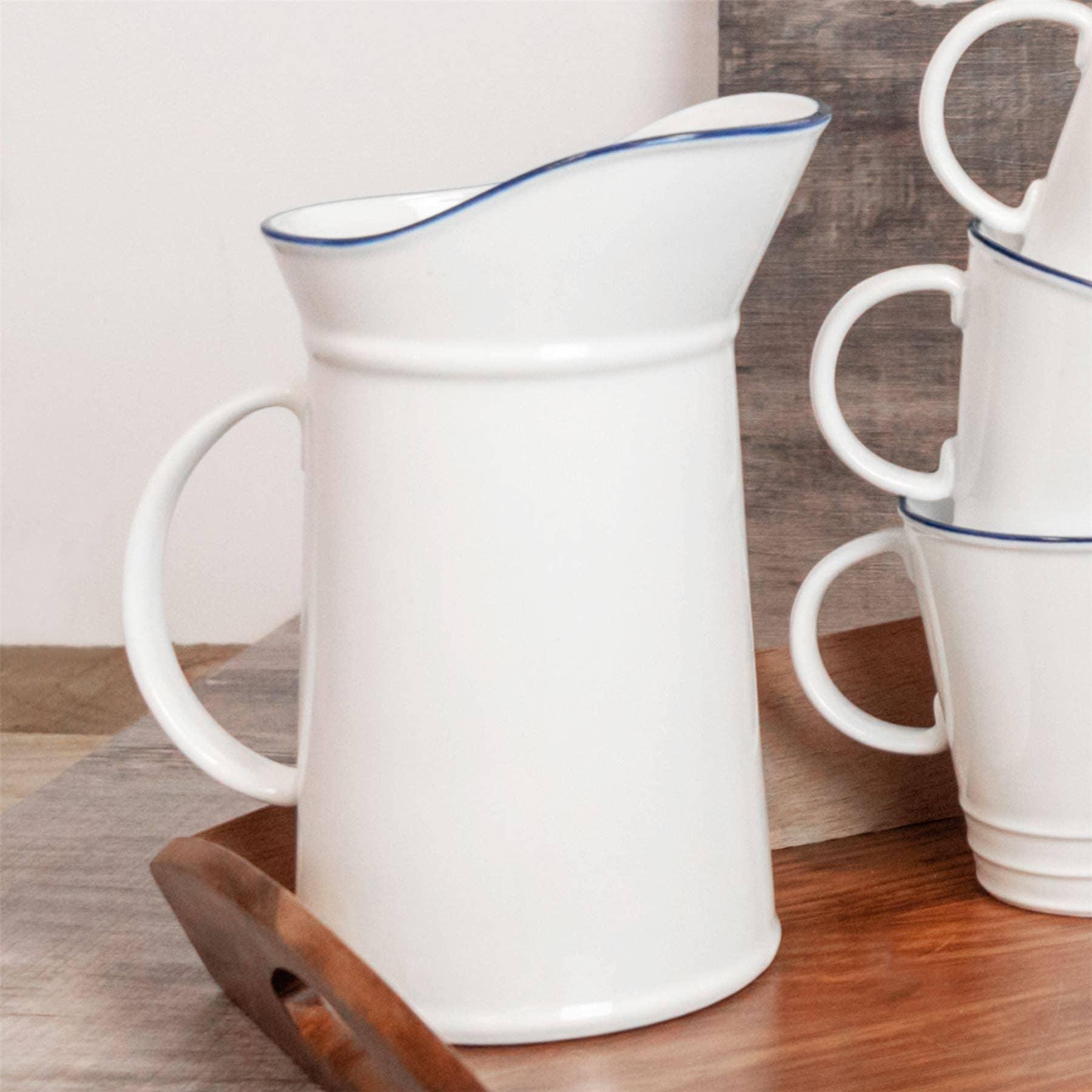 Casa Cubista white ceramic pitcher with blue rim and matching mugs on wood tray