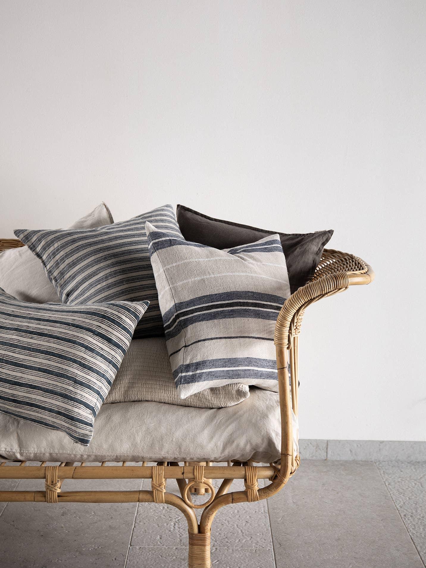 Tensira premium striped cotton pillows in blue and beige on a rattan sofa