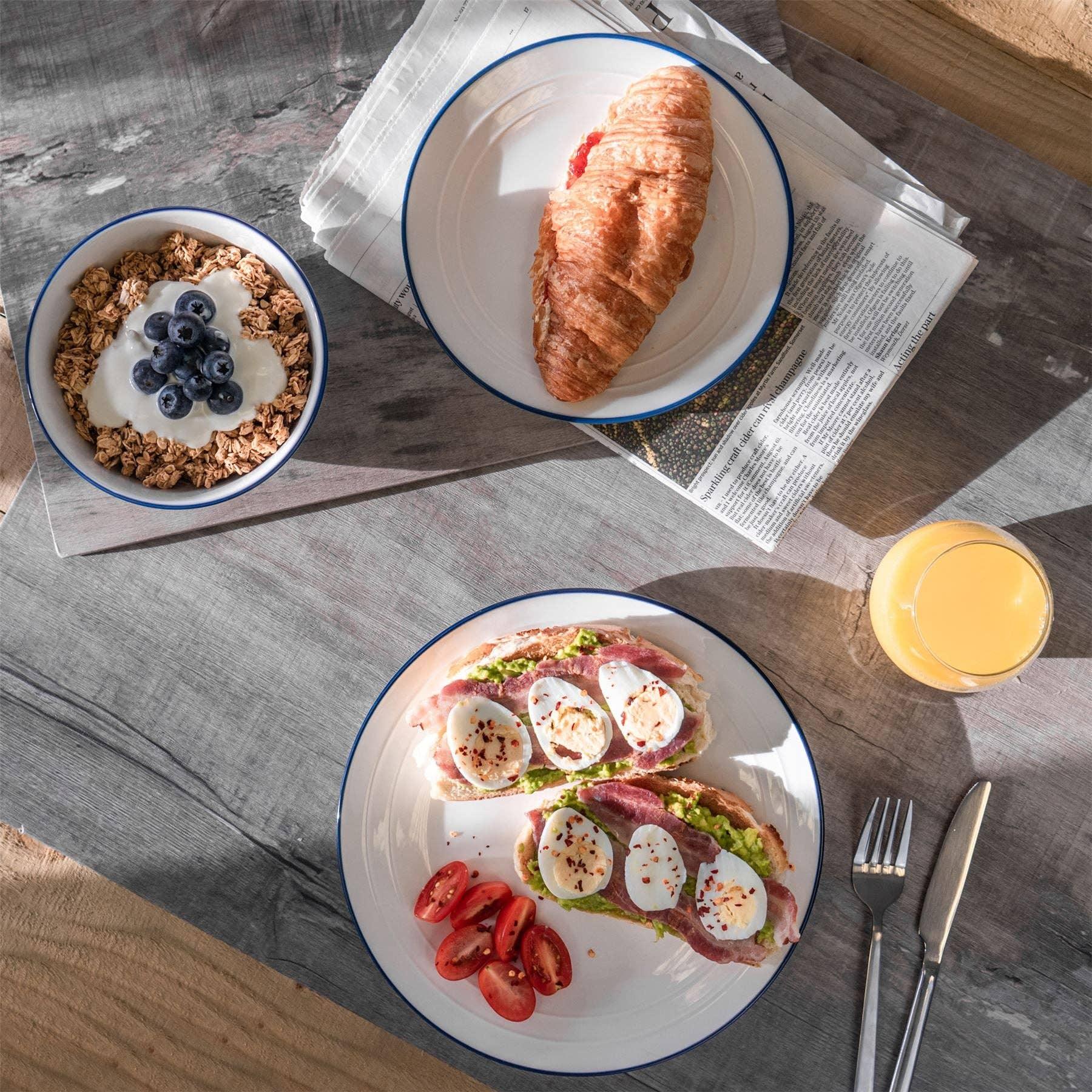 Hasami blue-rimmed ceramic plates and bowl with breakfast croissant, granola, eggs on toast.