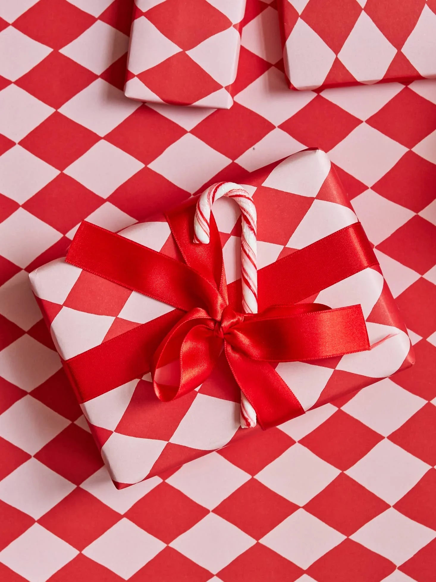 Anecdote gift wrap paper, red and white diamond pattern, premium paper, satin ribbon, candy cane accent.