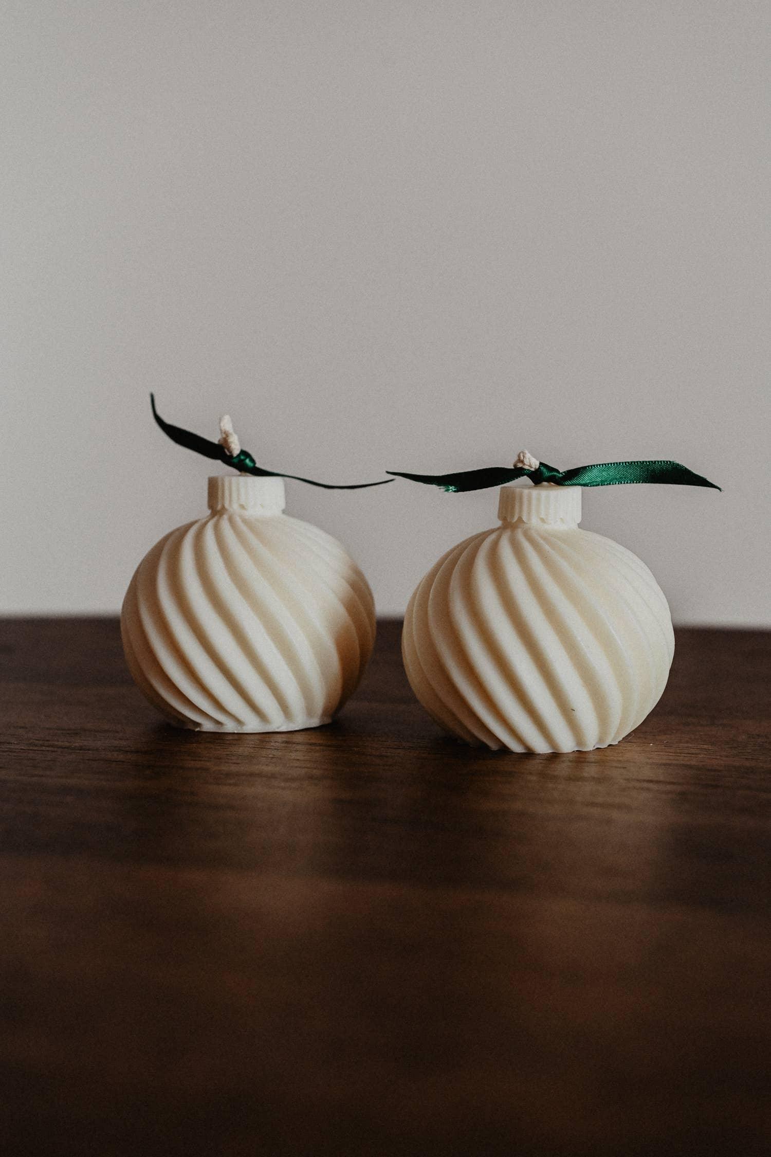 Everly candles cream soy wax swirl ornament shape with green ribbon on wood table