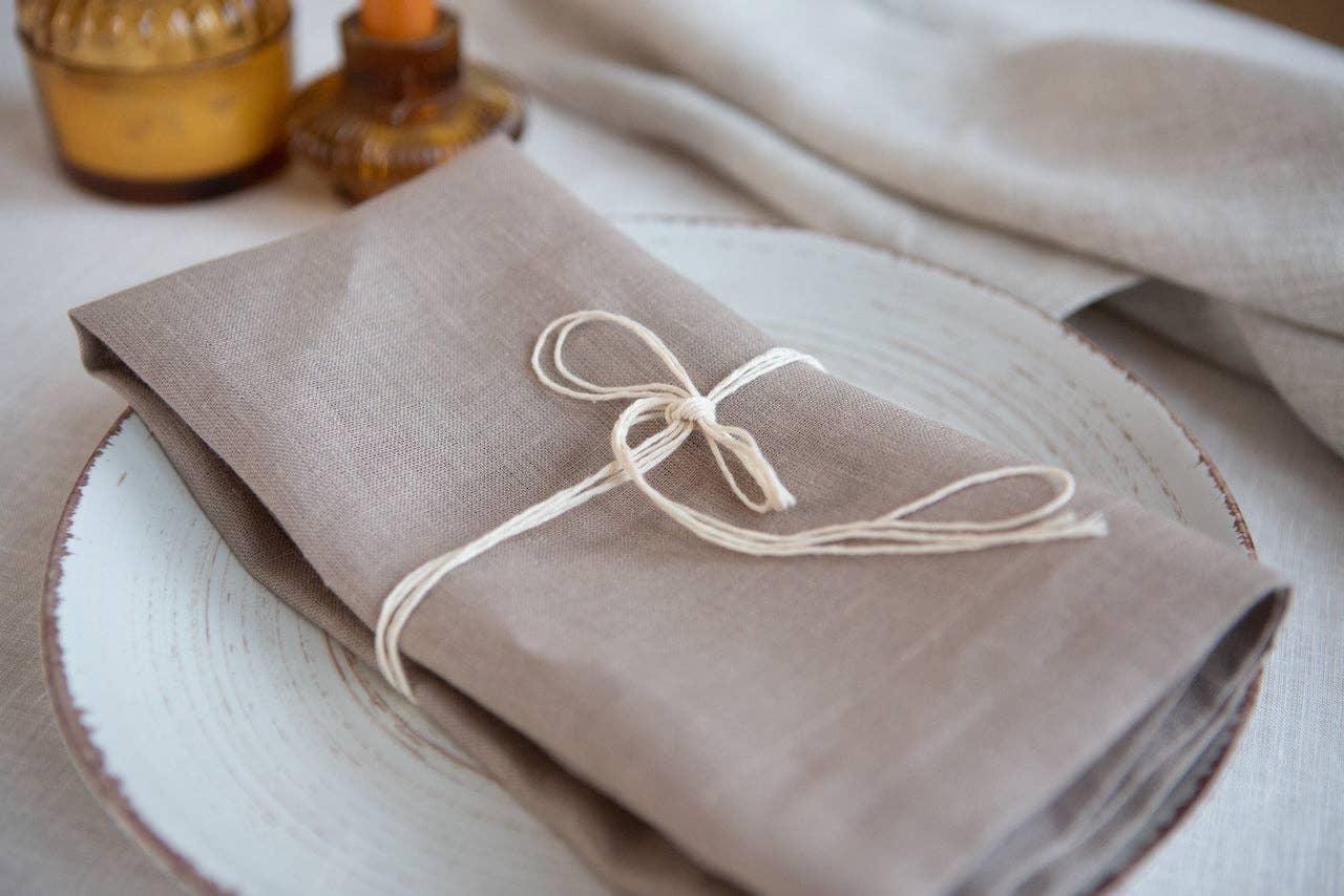 Linen Tales beige linen napkin tied with string on rustic ceramic plate
