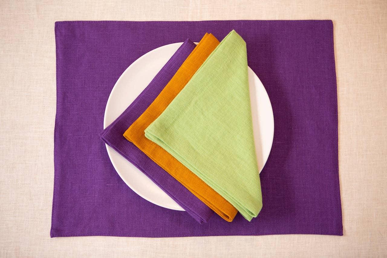 LinenDuet linen placemat in purple with green, orange, and purple linen napkins on white plate