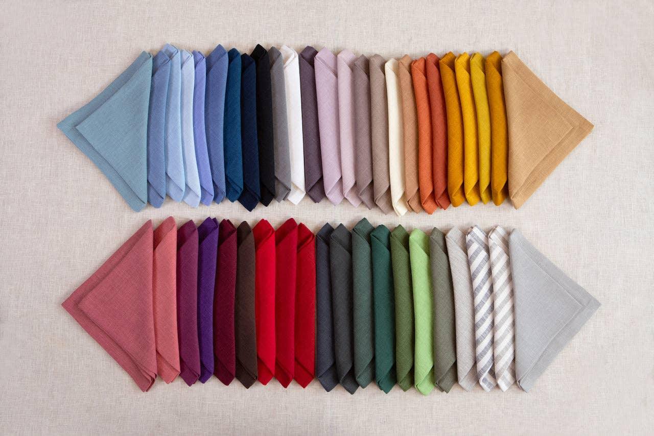 MagicLinen linen napkins in assorted colors, neatly folded on a neutral fabric background