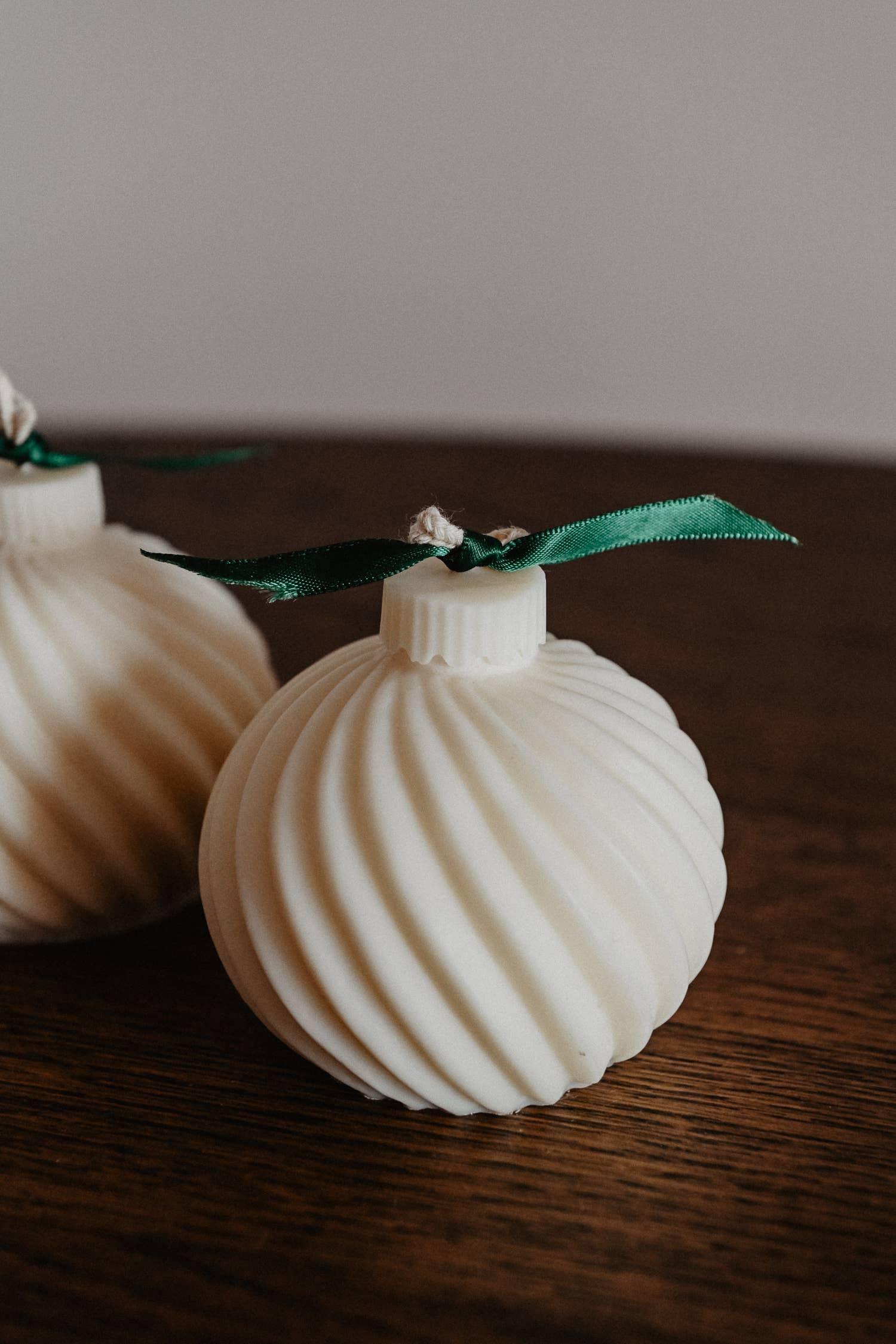 Flusso white soy wax candle ornament with green ribbon on wooden table