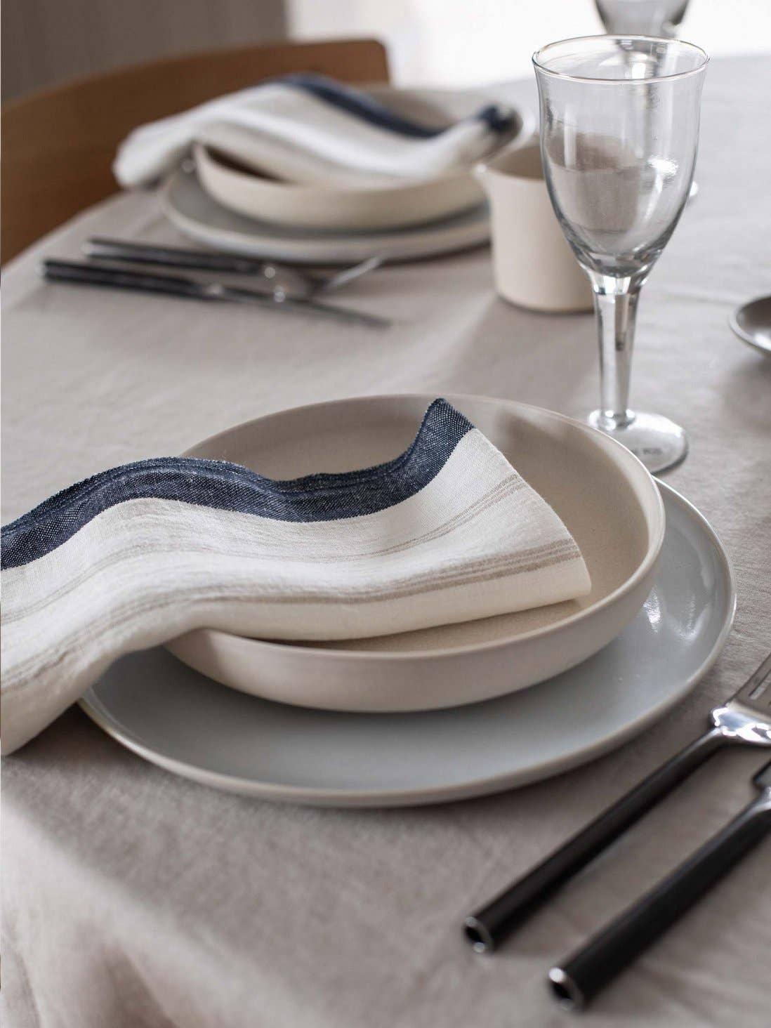 Fog Linen Work table setting with linen napkin, ceramic plates, glassware, neutral tones