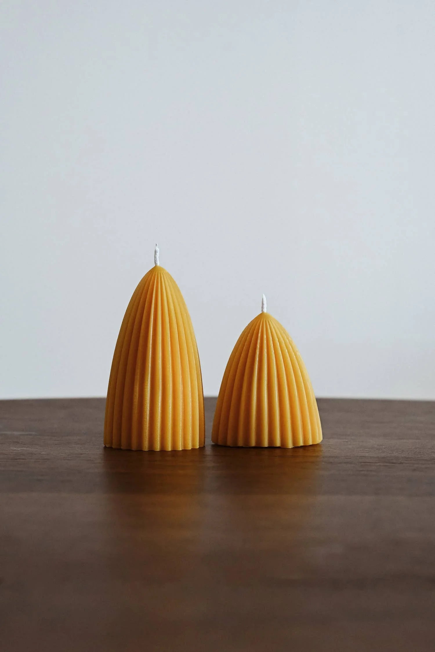 Moonday fluted beeswax candles, natural yellow, set on a wooden table