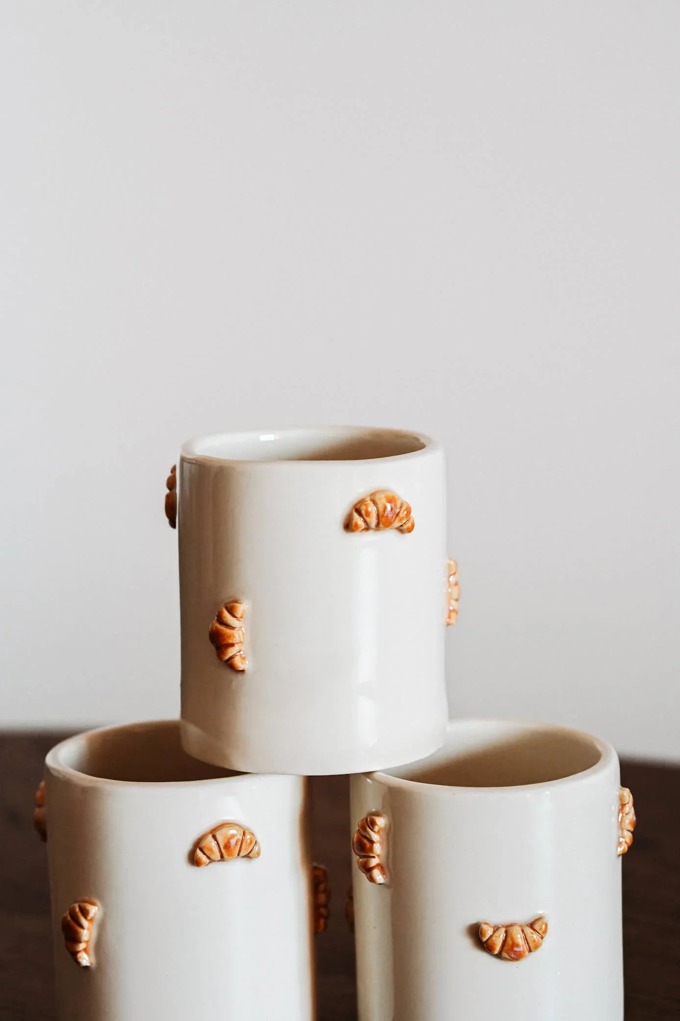 Iris Mint ceramic mugs with croissant detail, white stoneware, stacked on wood table