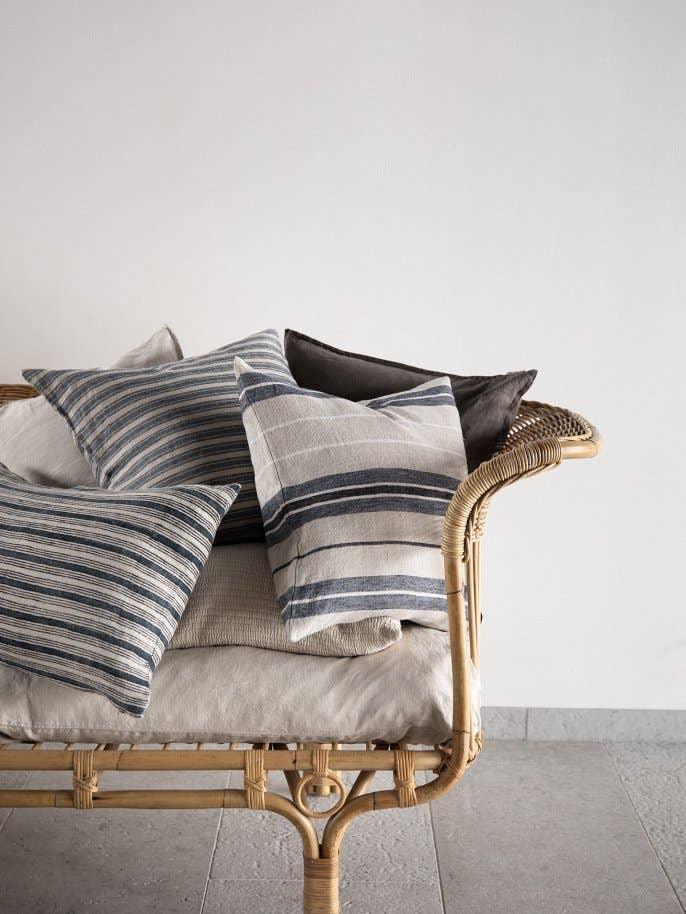 Tensira striped cotton pillows in blue and cream on rattan bench with neutral cushion
