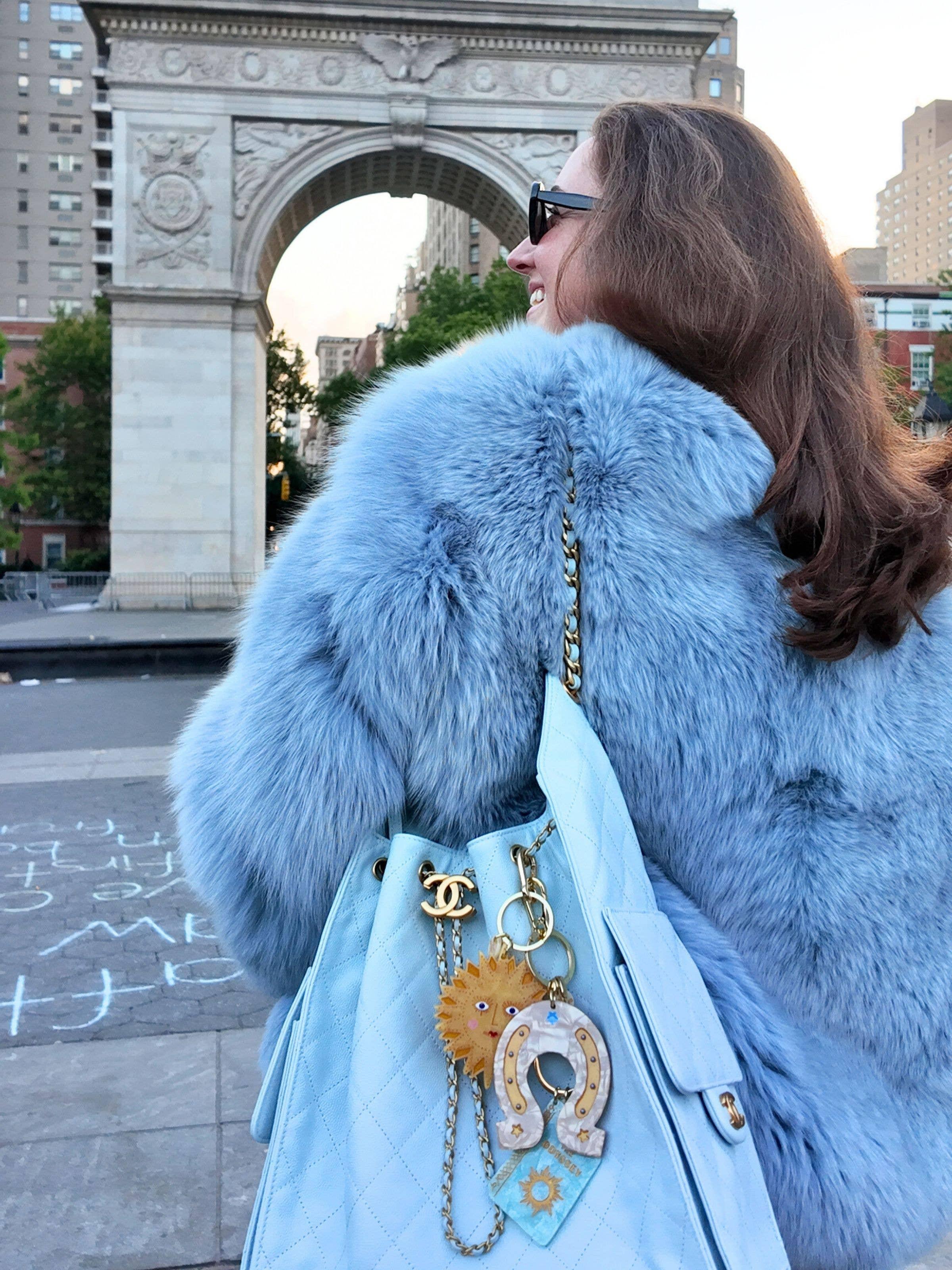 Chanel light blue quilted leather handbag with gold hardware, blue faux fur coat, outdoors