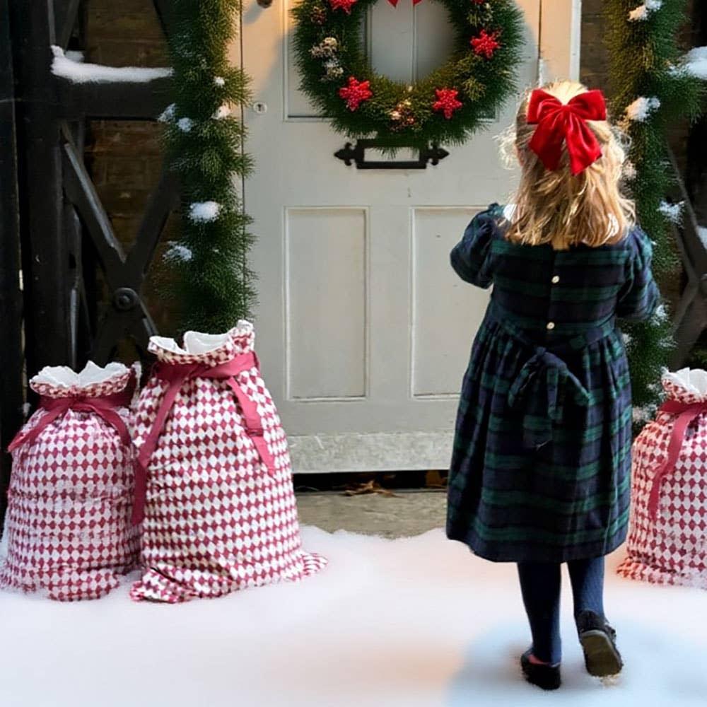 Powell Craft cotton Christmas gift sacks with red and white pattern by snowy door, girl in plaid dress