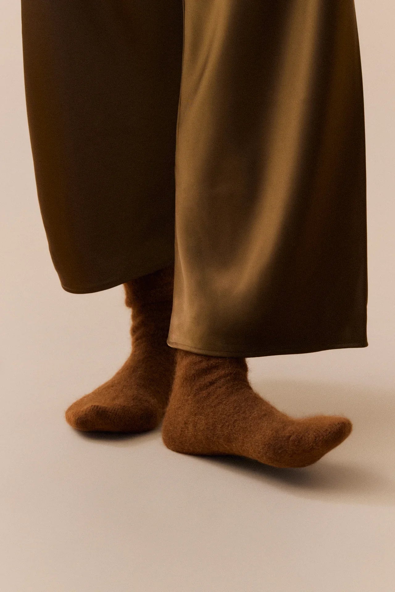 Le Kasha brown cashmere socks and wide-leg silk trouser hem in neutral setting