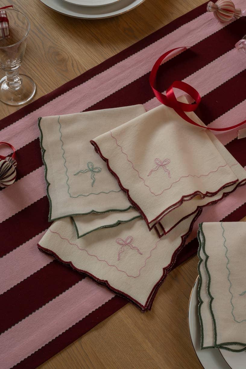 Misette linen napkins with scalloped edges and embroidered bow on pink and burgundy table runner