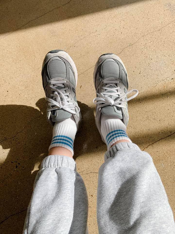 New Balance grey mesh sneakers with white laces, worn with grey sweatpants and white socks
