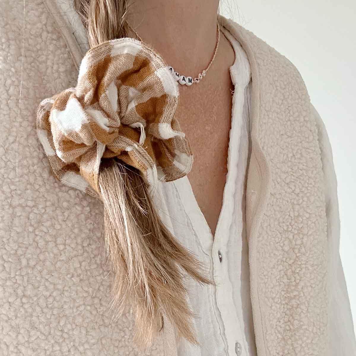 SEA + PINE brown plaid cotton scrunchie in blonde hair, cream sherpa vest, white shirt