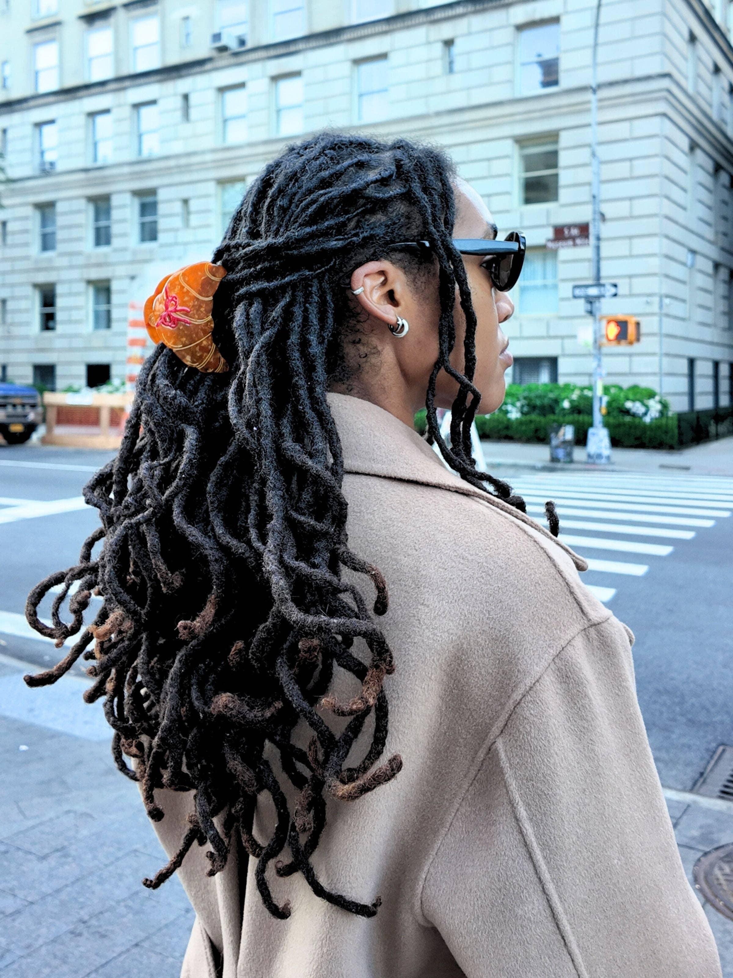 Tress Noir hair clip in amber resin holding dreadlocks, street style, taupe wool coat