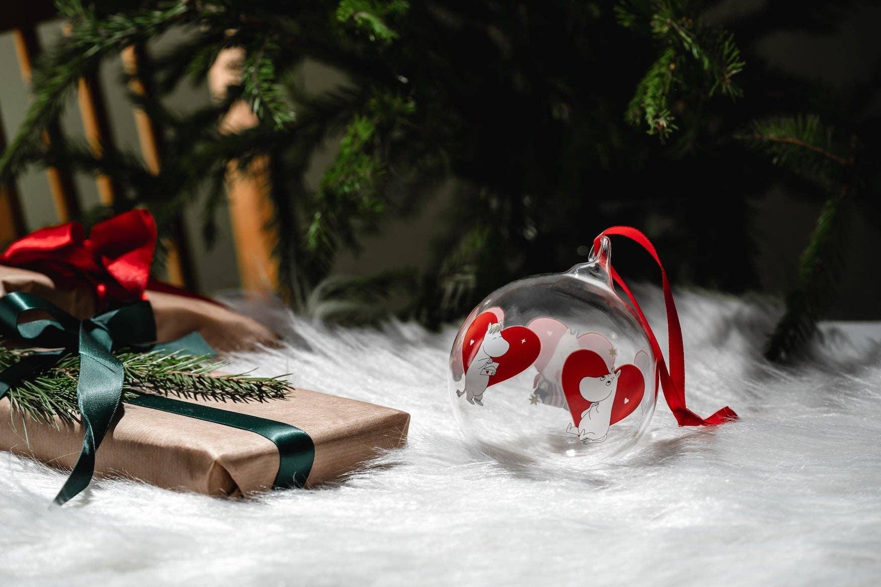 Moomin glass Christmas bauble with red heart illustrations and red ribbon on white fur